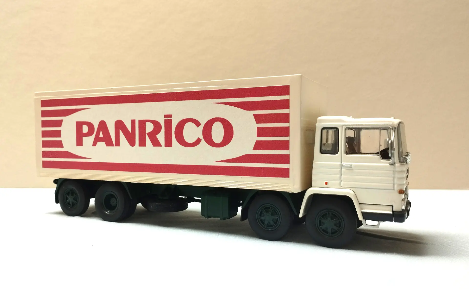 Un camión blanco con "PANRICO" en letras rojas en el costado, estacionado sobre una superficie clara, perfecto para coleccionistas de maquetas de camiones o fanáticos de los camiones a escala 1:43.