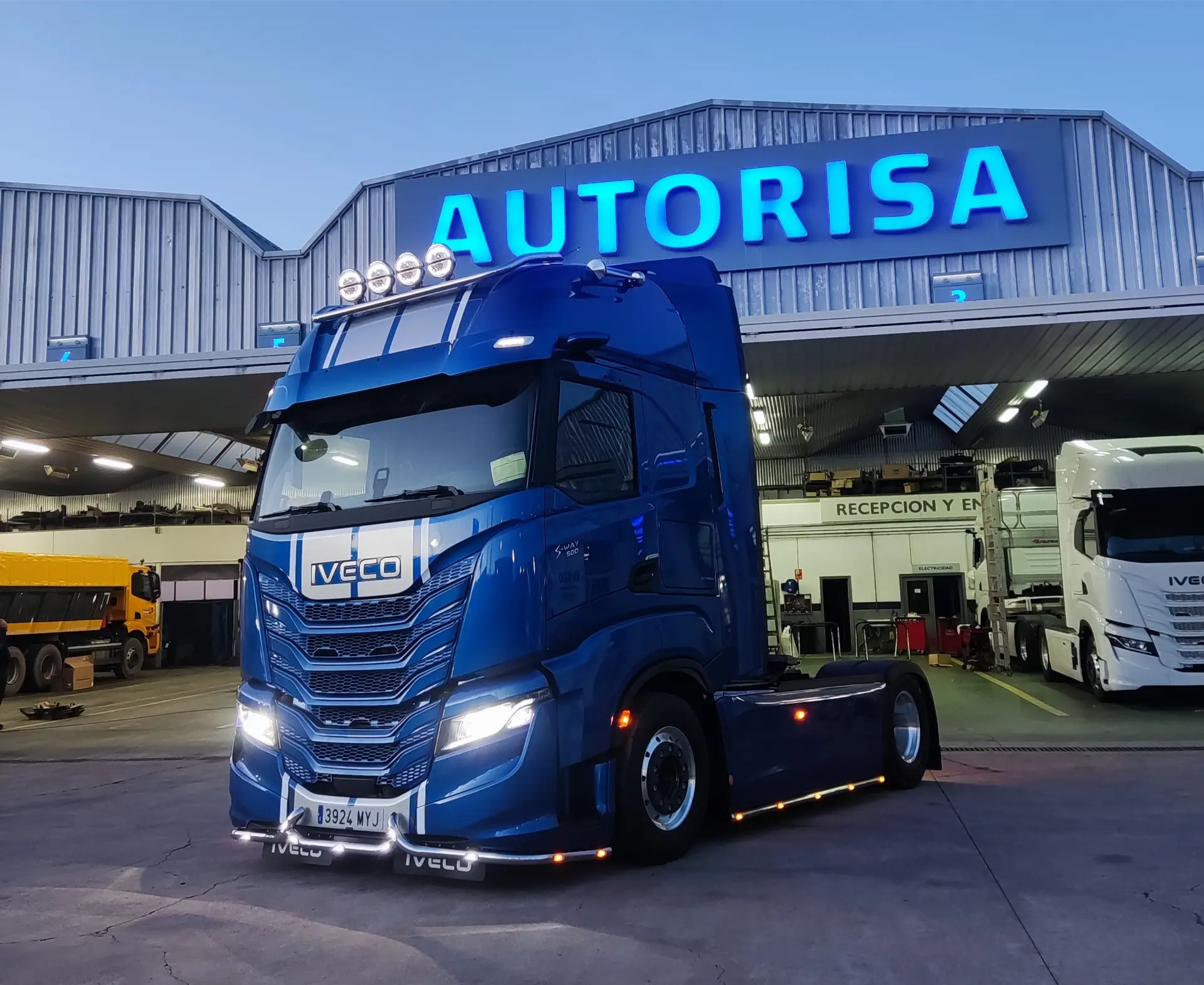Un camión Iveco azul de Solo Camión está estacionado frente a un edificio con un cartel azul brillante que dice "AUTORISA".