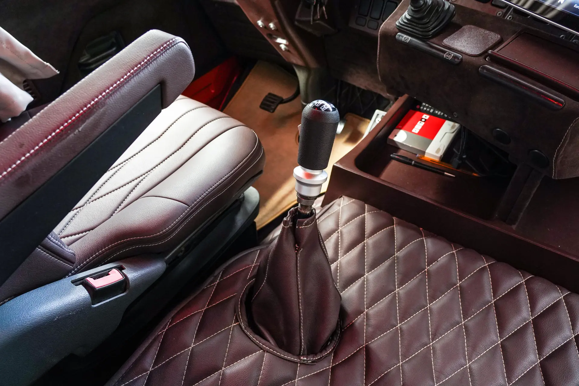 Primer plano del interior de cuero marrón de un coche, con la palanca de cambios y el asiento del conductor centrados en su borrador automático para una conducción fluida.