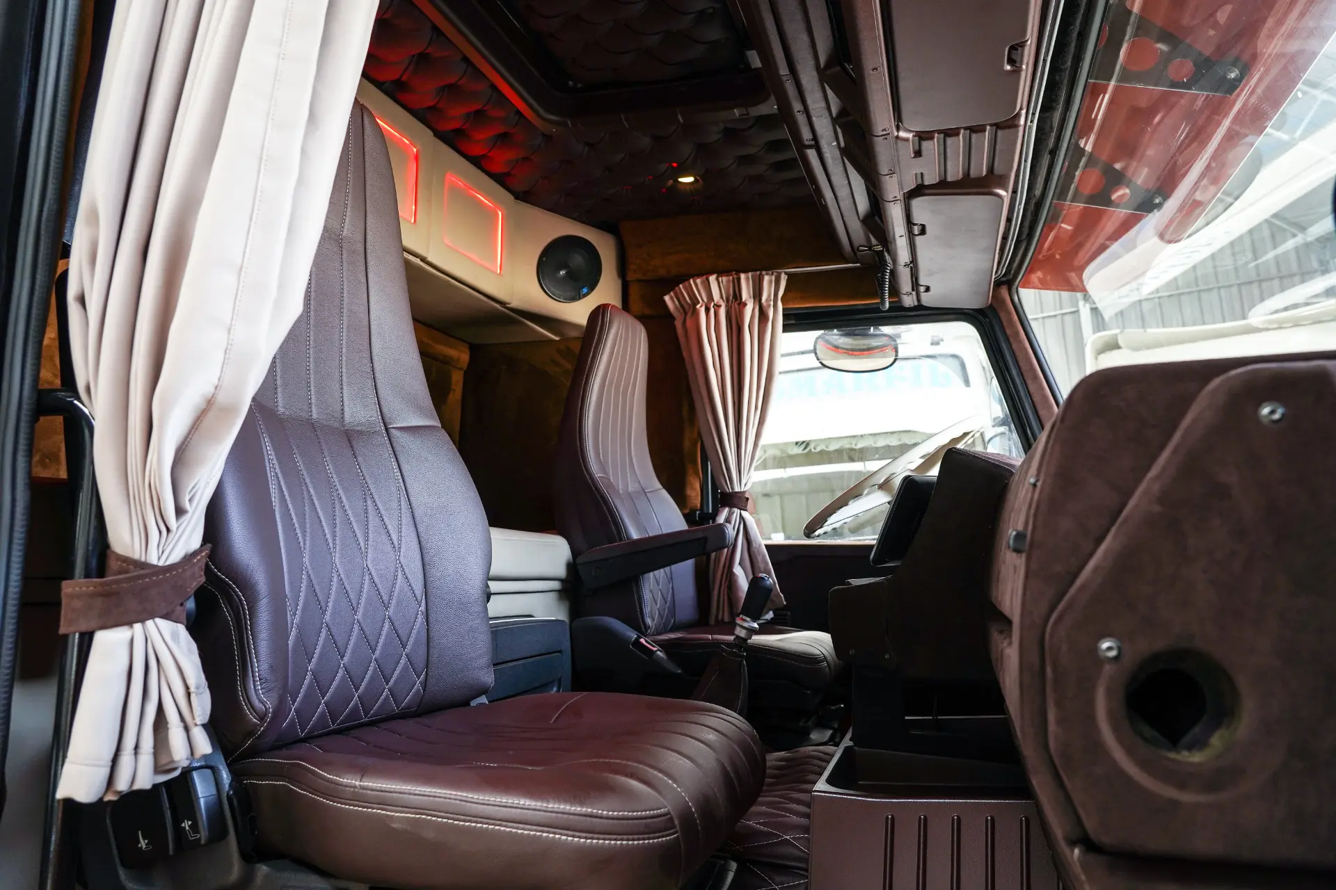 Vista interior de la cabina de un camión con asientos y cortinas de cuero marrón, con un diseño moderno y limpio y un cómodo borrador automático para mayor funcionalidad.