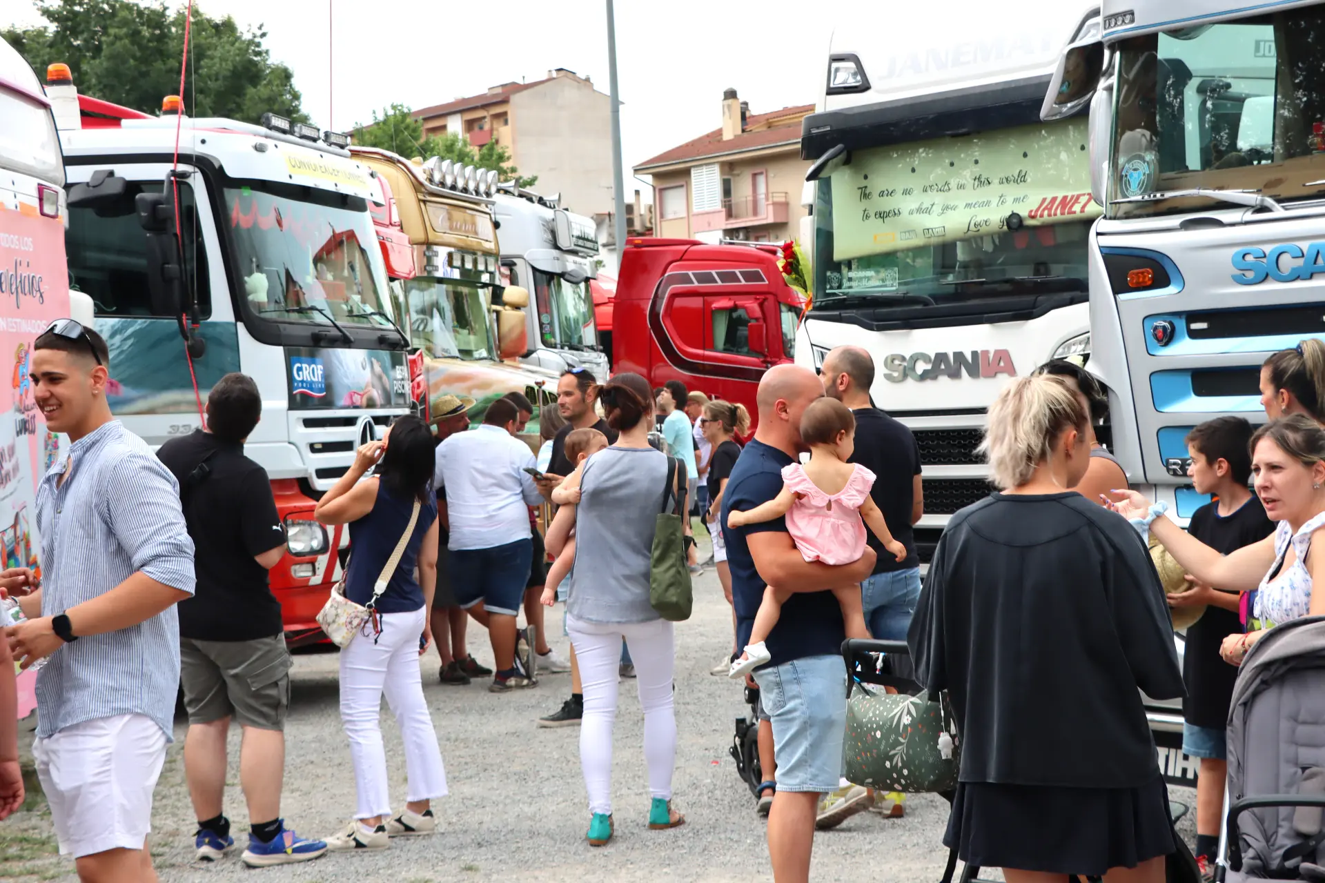 La gente se reúne y socializa entre camiones de colores aparcados en una concentración de camiones en Olot en un día soleado.