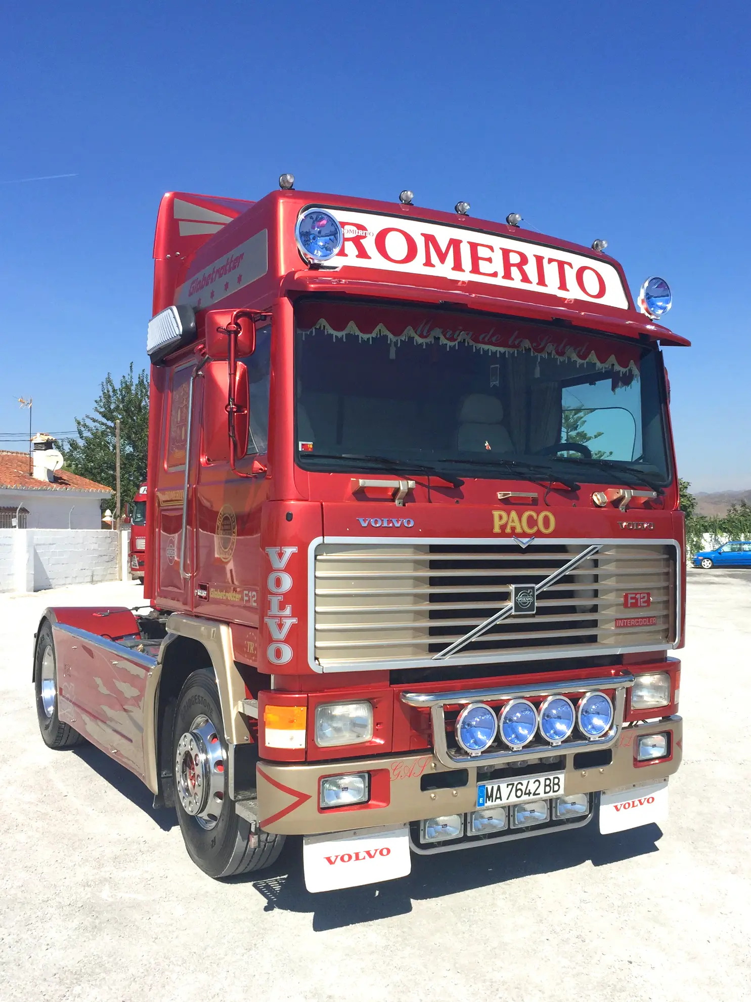 Camión Volvo rojo rotulado "ROMERITO" y "PACO", aparcado al aire libre en un día soleado, representando a Transportes Romerito-una de las empresas de Málaga especializadas en transportes de mercancías.