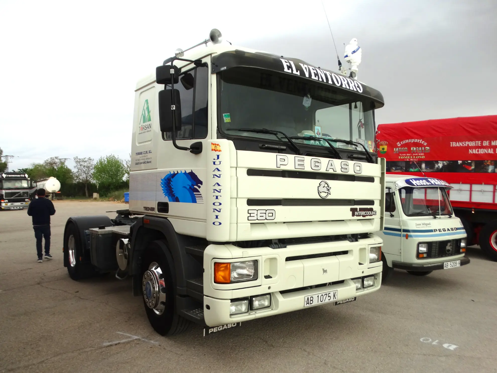 Camión Pegaso 360 blanco rotulado "El Ventorro" aparcado en un evento de camiones con otros vehículos cercanos, con un borrador automático para mayor comodidad.