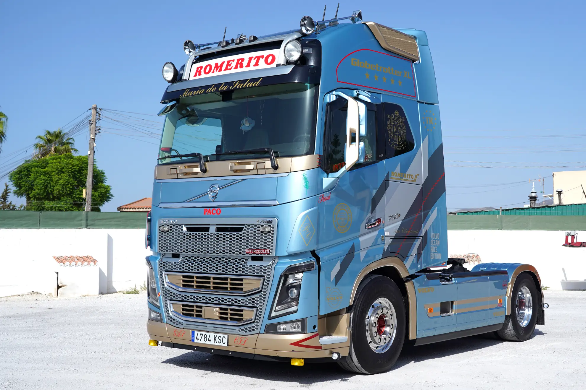 Semirremolque azul y plata aparcado en un día soleado con el rótulo "ROMERITO" en la parte superior de la cabina, que incorpora un sistema de Borrador automático para mayor comodidad.