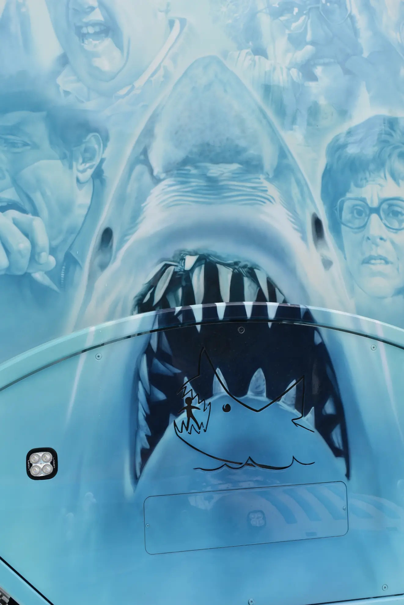 Un mural de un tiburón con las fauces abiertas y la cara afligida, inspirado en "Tiburón" de Spielberg, crea una escena dramática en el lateral de un Scania 770 S camión personalizado.