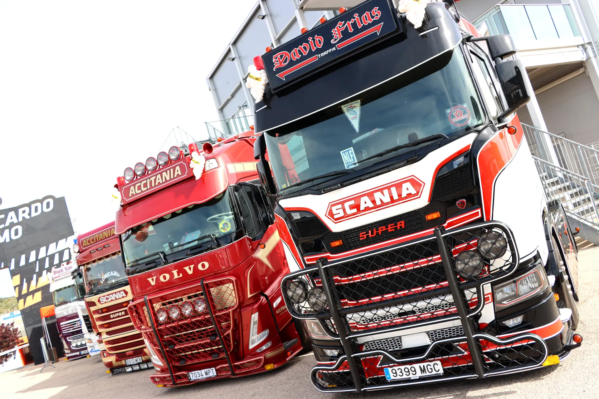 Tres camiones decorados, entre ellos de las marcas Scania y Volvo, aparcados uno junto al otro en un evento al aire libre.