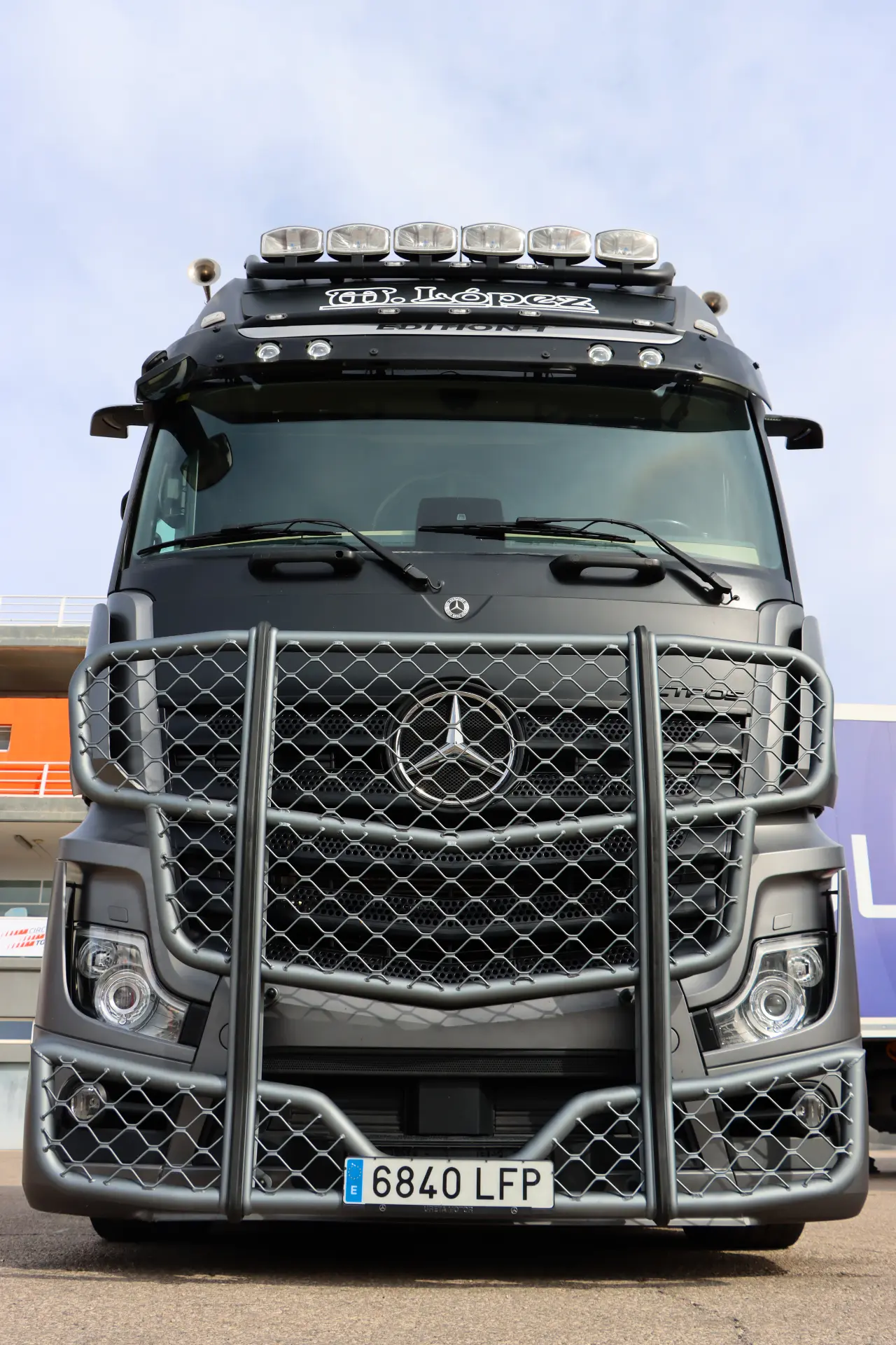 Camión Mercedes-Benz negro con protector de parrilla metálico, fotografiado de frente en un día despejado.