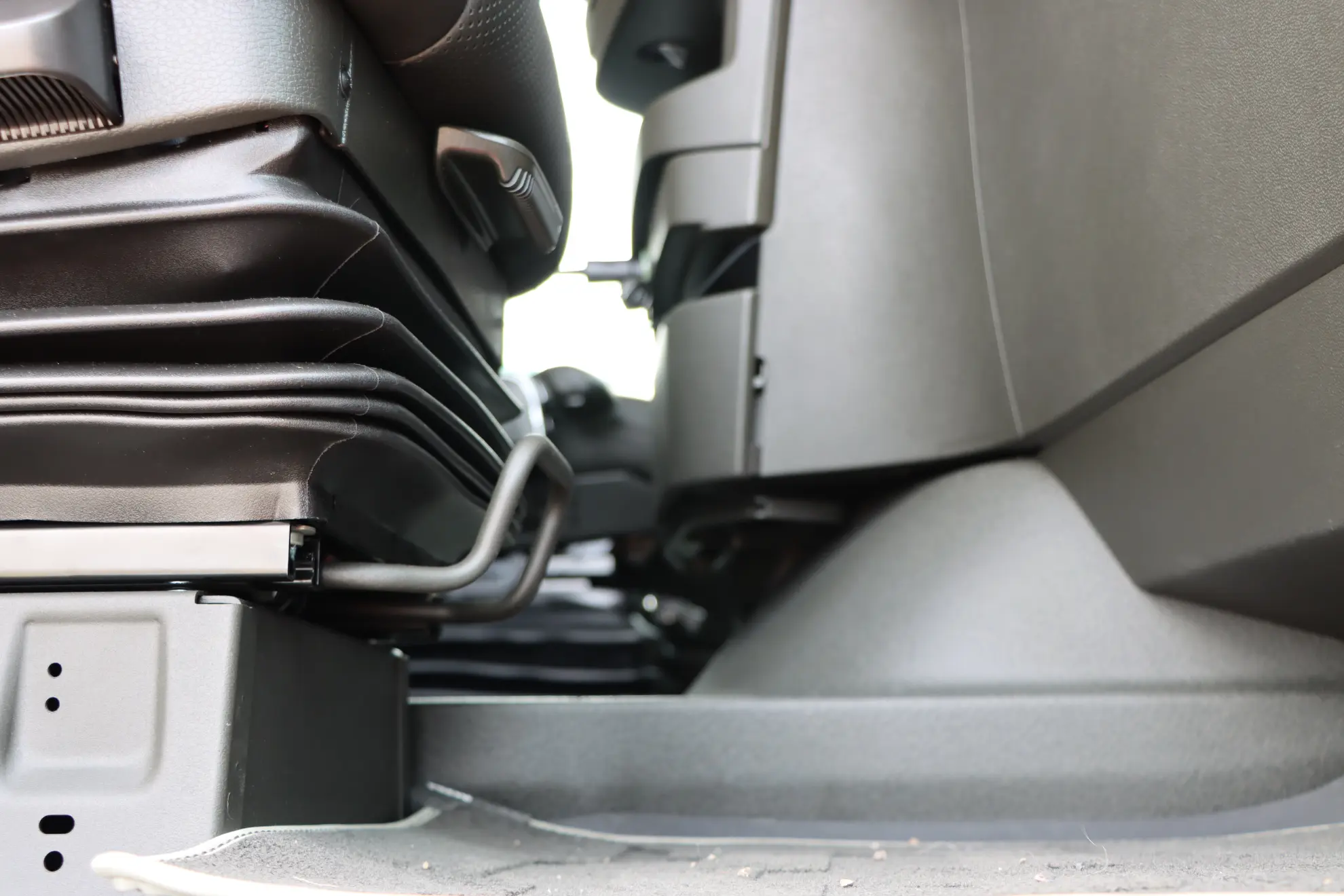 Primer plano del espacio bajo dos asientos de coche en un vehículo, centrándose en los detalles del asiento y el suelo en un entorno de gestor de flotas para camiones a gas.