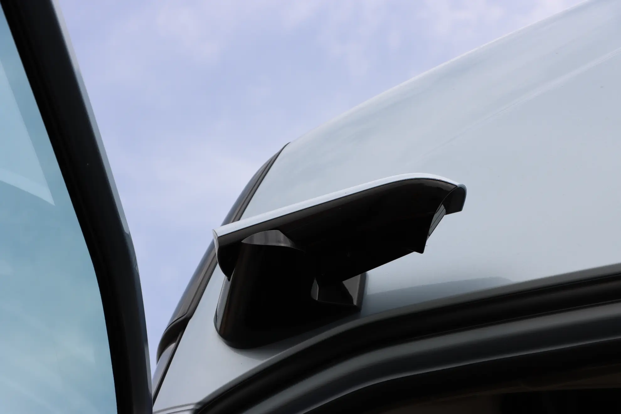 Primer plano de un retrovisor lateral digital en un vehículo Volvo a gas, con un cielo azul de fondo.
