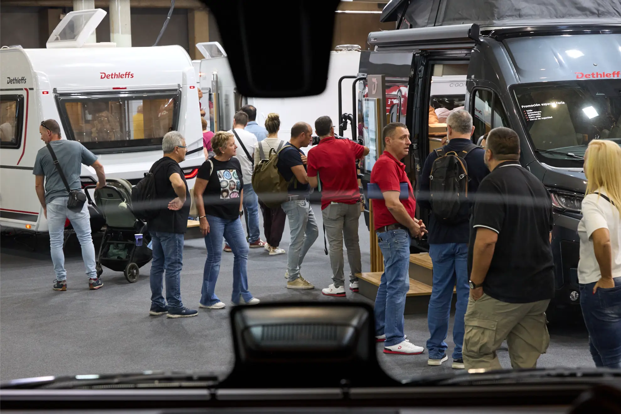 La gente pasea y se reúne en torno a caravanas y autocaravanas en el Salón del Caravaning, una exposición o muestra comercial cubierta.