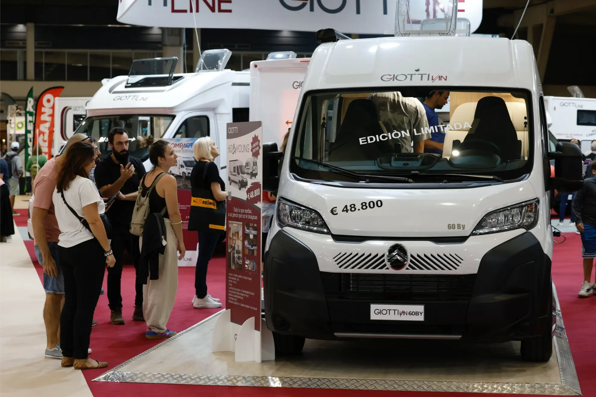Un grupo de personas examina una caravana GiottiLine blanca con un precio de 48.800 euros en el Salón del Caravaning, una exposición de vehículos de interior.