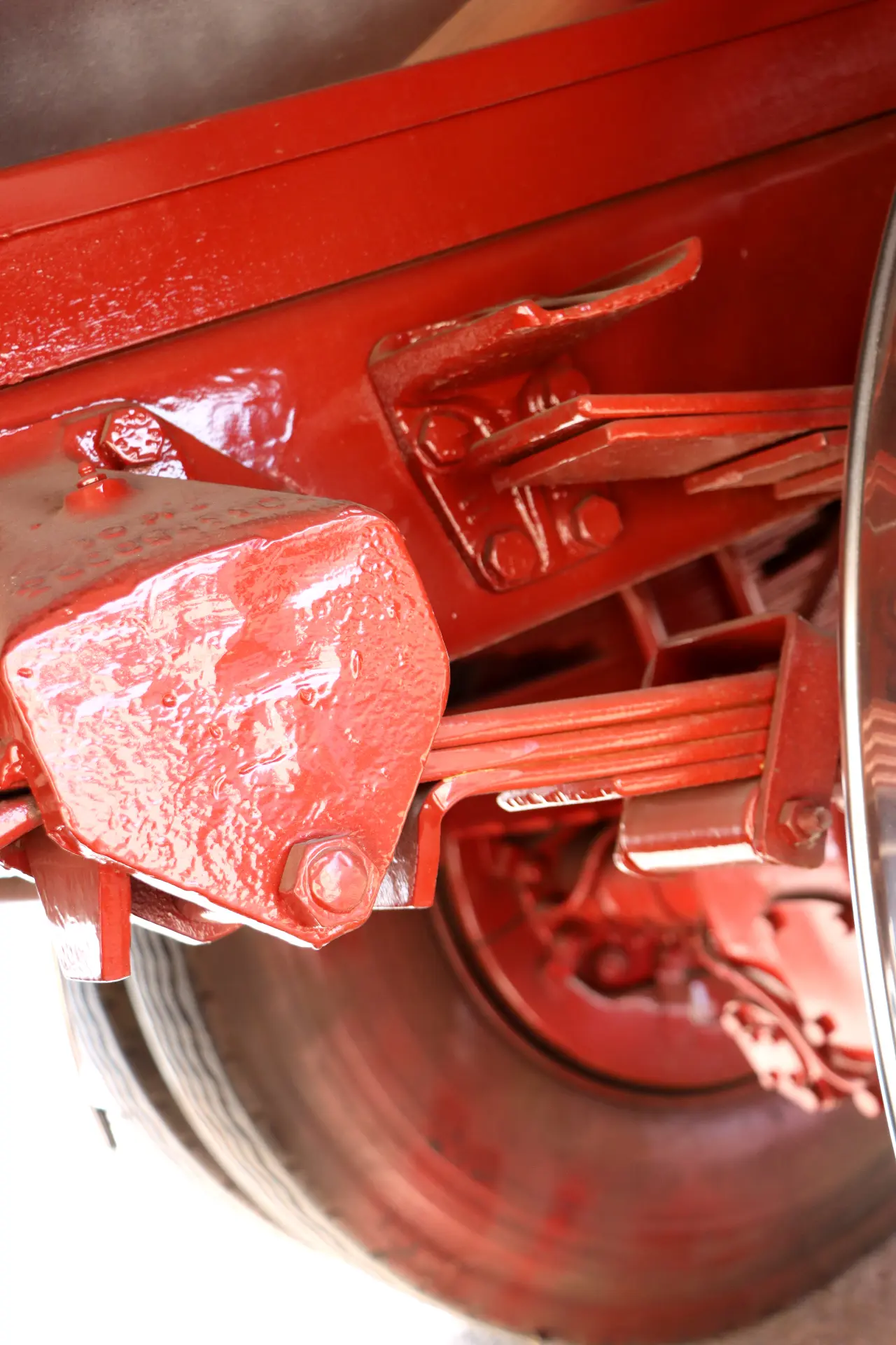 Primer plano de piezas mecánicas pintadas de rojo y de una rueda, posiblemente parte del sistema de suspensión de un vehículo.