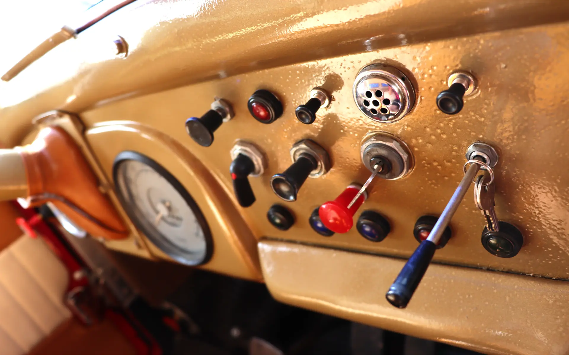 Primer plano del salpicadero de un coche antiguo con múltiples interruptores, palancas, botones y un indicador.