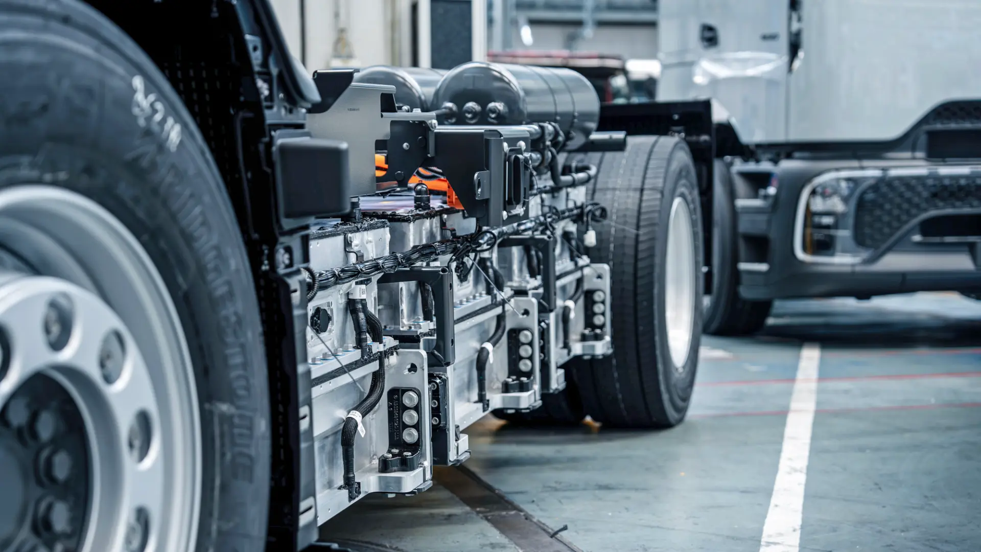 Primer plano de un chasis de camión eléctrico con paquetes de baterías y componentes, con un sistema Borrador automático en el interior de un almacén.