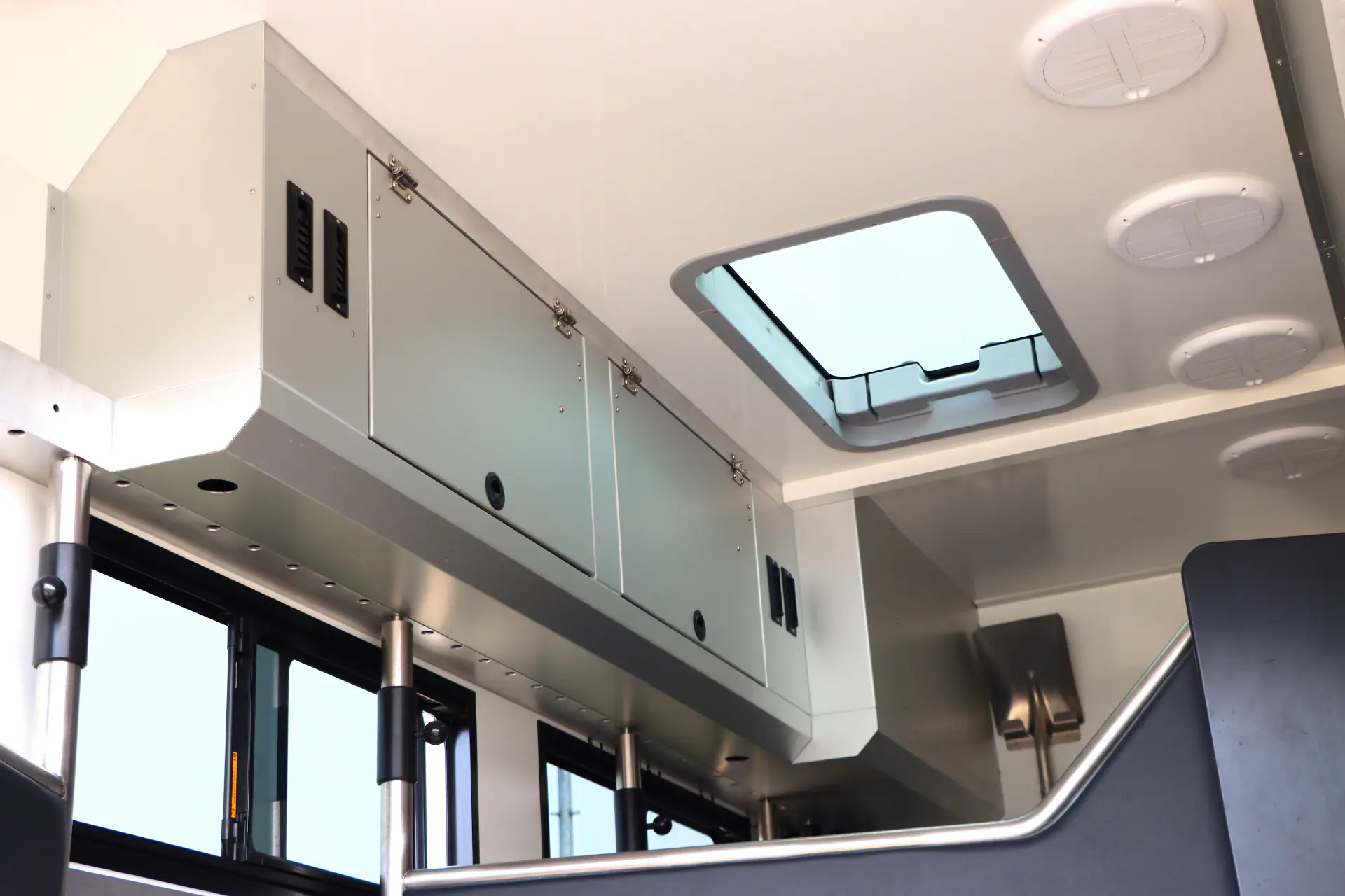 Vista interior de un autobús con compartimentos superiores de almacenamiento, una claraboya rectangular en el techo y un panel automático Borrador perfectamente integrado para mayor comodidad.