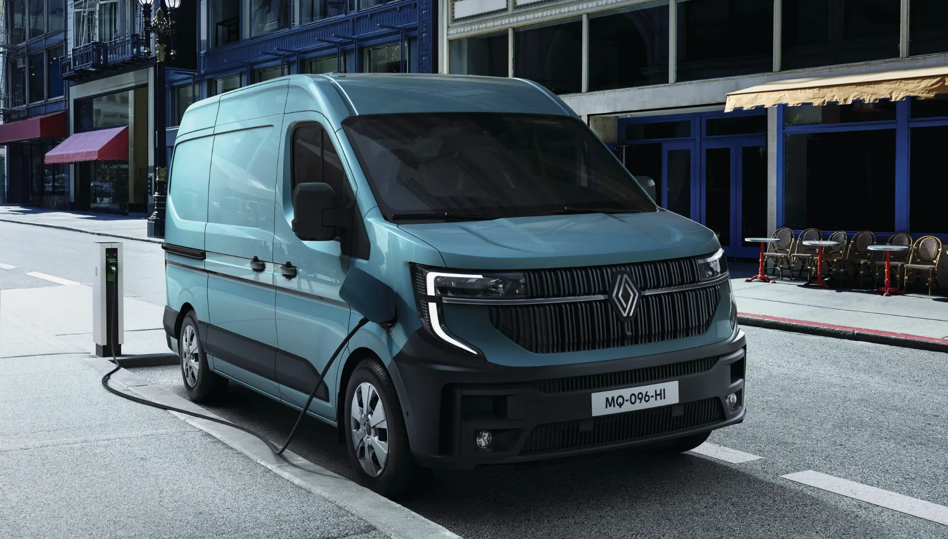 Una furgoneta eléctrica Renault azul se carga en una estación de recarga callejera en un entorno urbano, mostrando la comodidad del borrador automático para los conductores modernos.