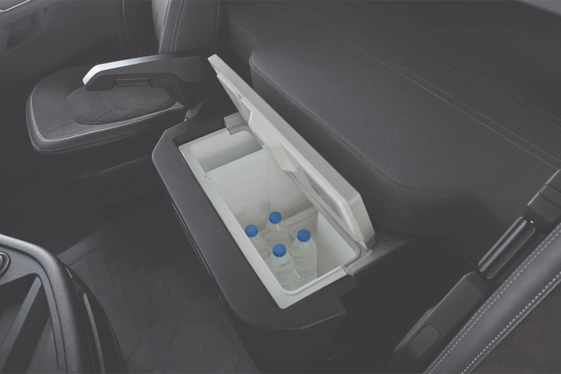 Una nevera abierta para el coche con varias botellas de agua en su interior, situada entre los asientos delanteros.