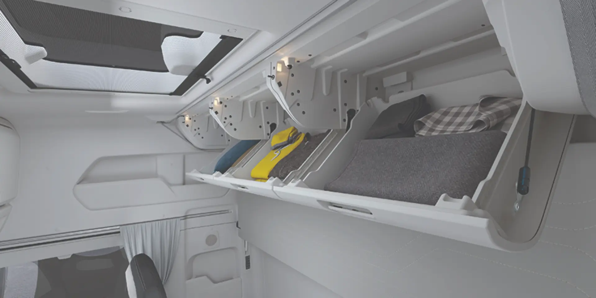 Compartimentos superiores de almacenamiento en la cabina de un vehículo, que contienen bolsas, almohadas y mantas.