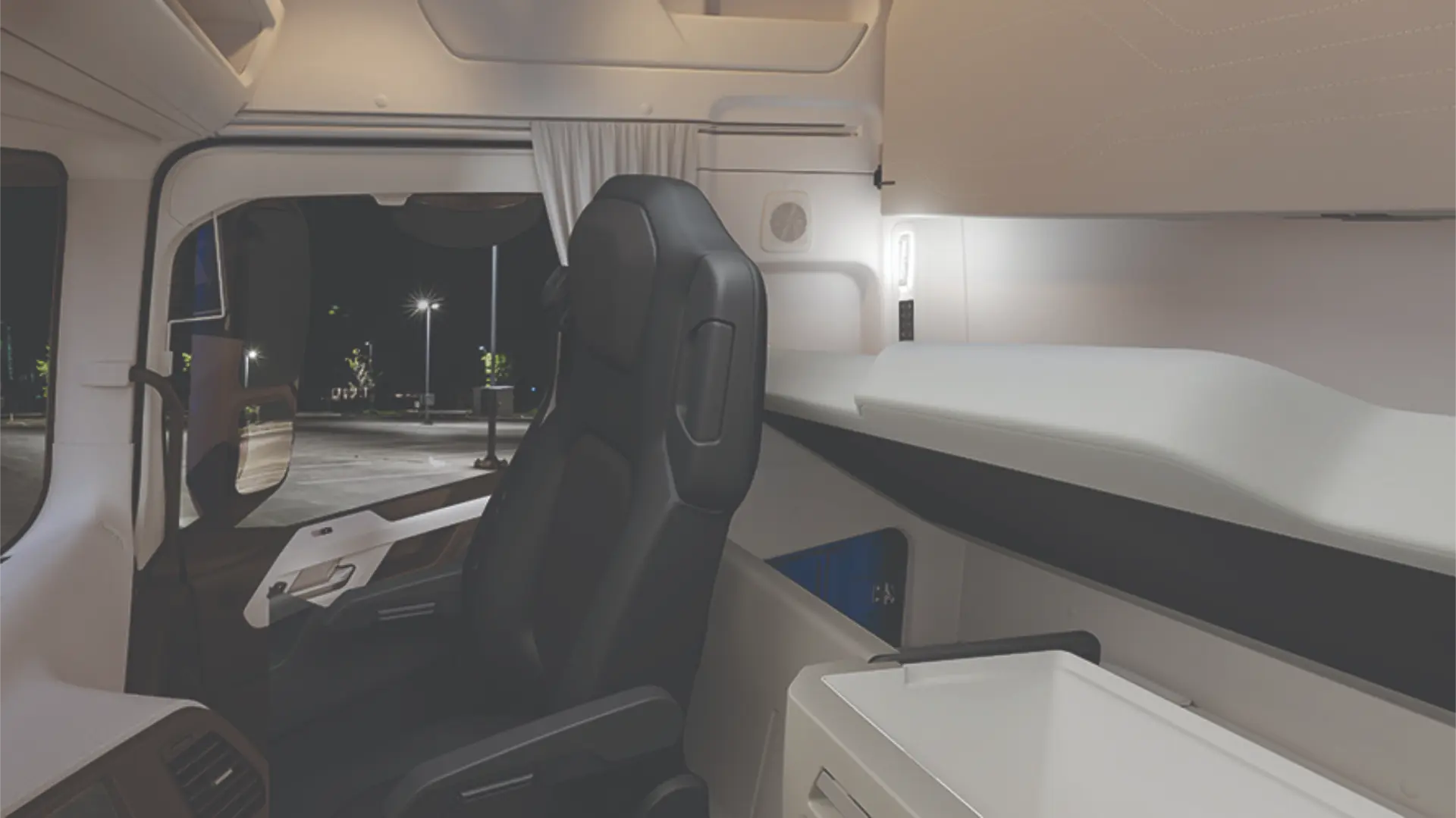 Interior de una cabina de camión moderna por la noche, con asiento del conductor, litera y compartimento superior.
