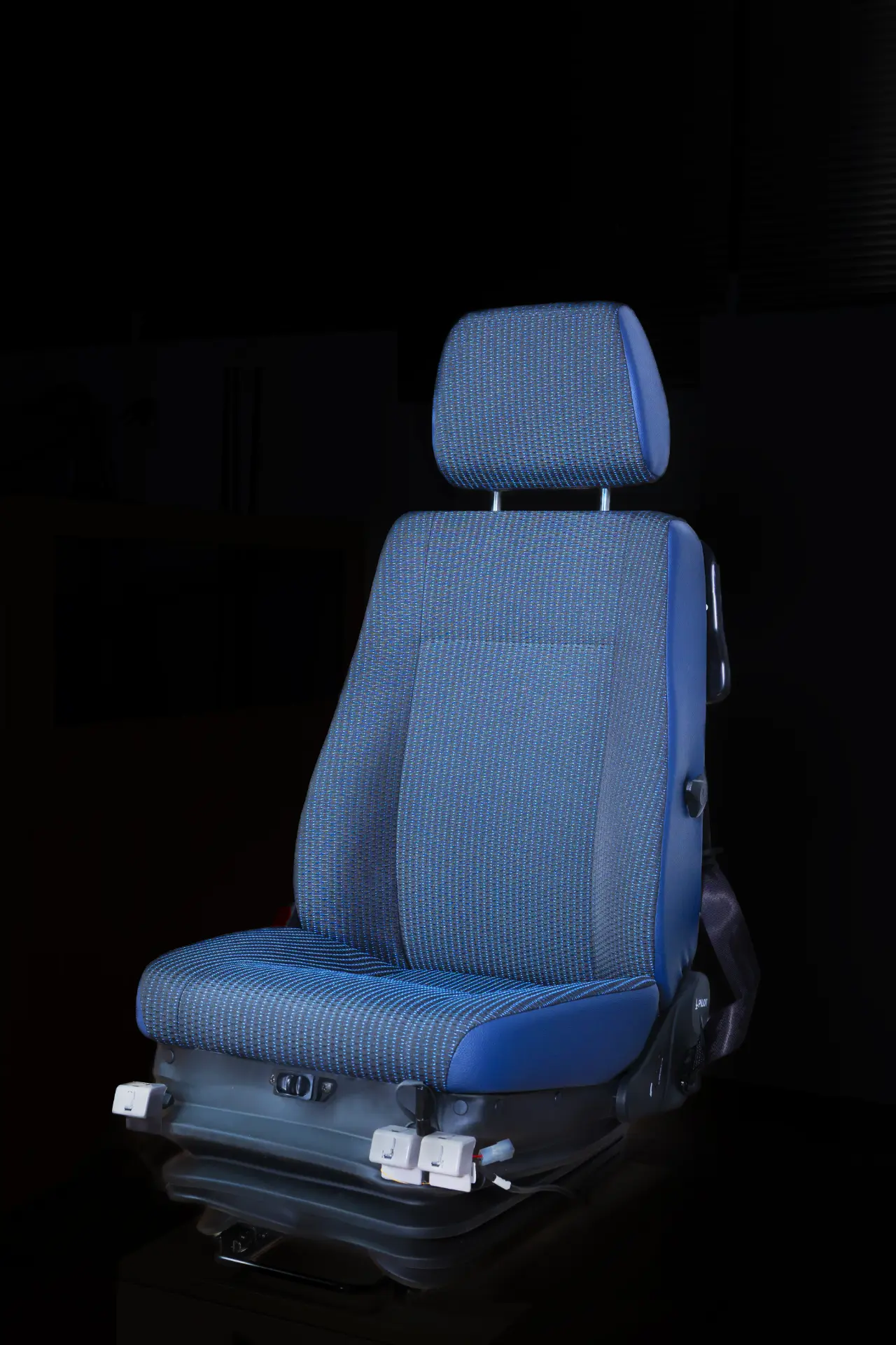 Silla de coche azul con reposacabezas y cinturón de seguridad, con un diseño elegante sobre fondo oscuro, perfecta para vehículos con sistemas de seguridad de borrador automático.