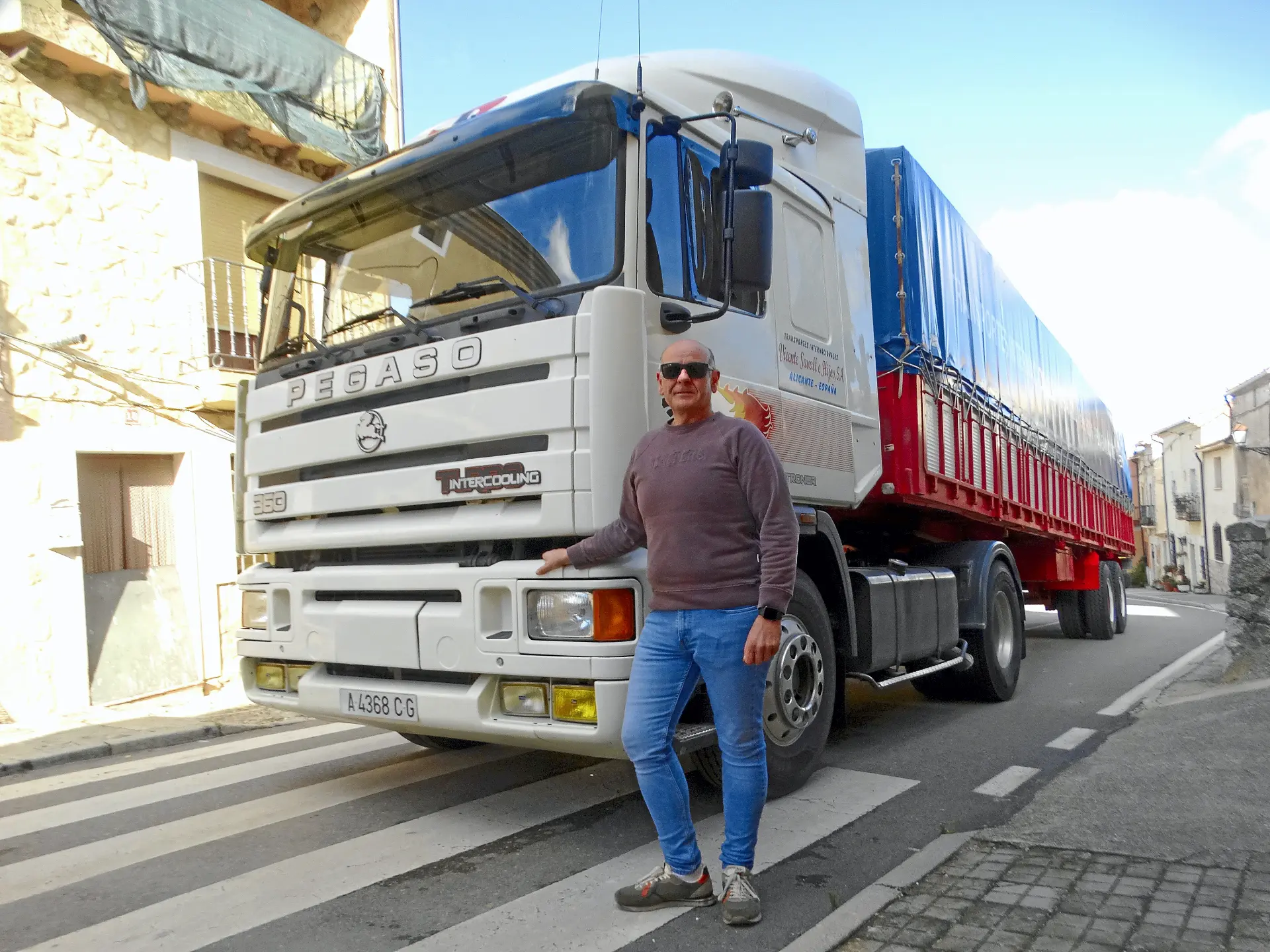 Un hombre con gafas de sol sonríe delante de un gran camión Pegaso, uno de los camiones clásicos que se ven a menudo por la Ribera del Duero.