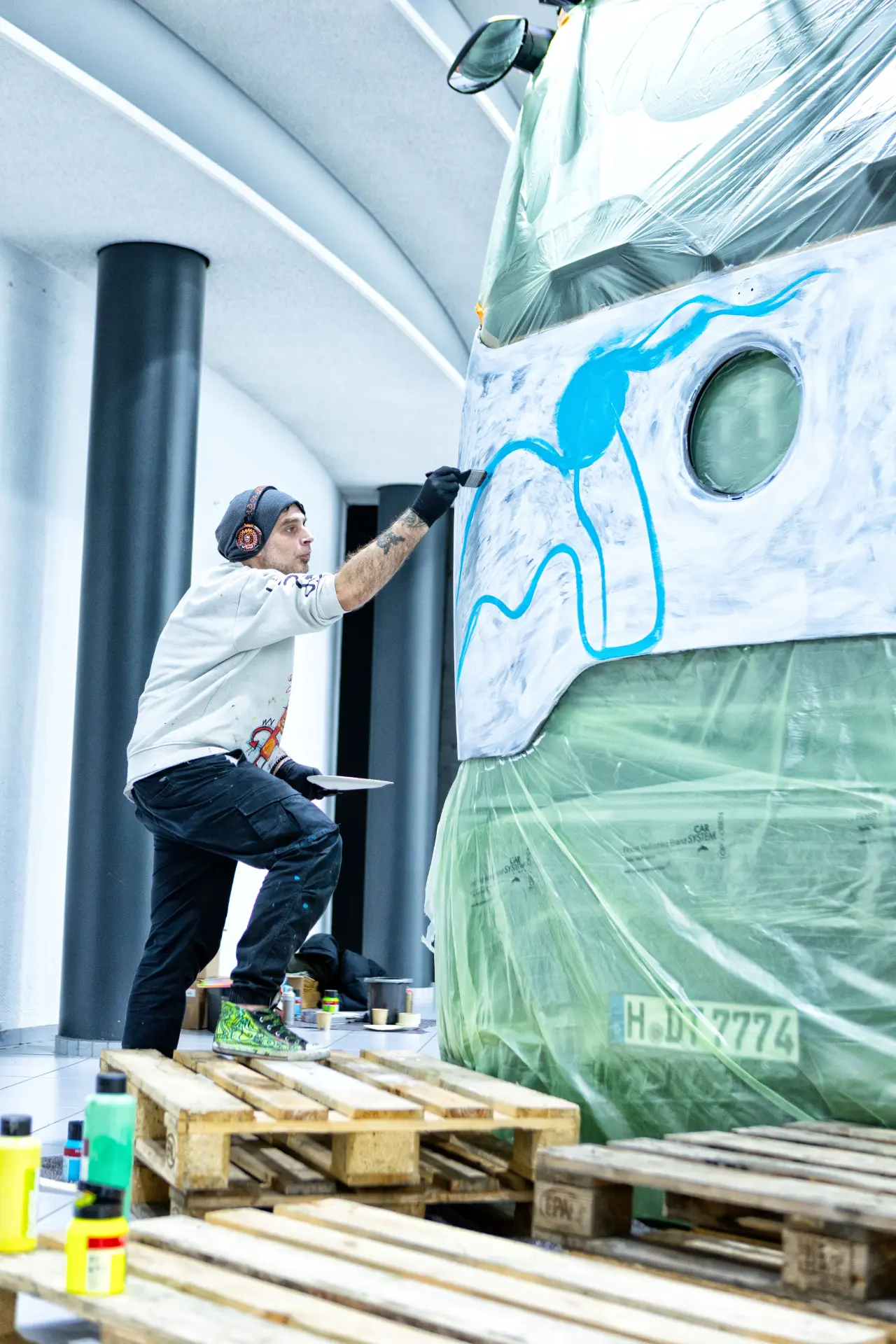 Un artista pinta un diseño en el interior de un Actros edición art truck, colocado sobre un palé de madera.