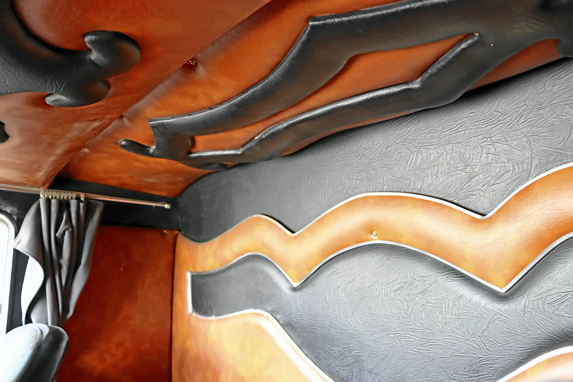 Interior de automóvil en cuero marrón y negro con diseños ondulados y abstractos acolchados en la pared y el techo, inspirados en el estilo Cresmotrans Náuticos & Especiales visto en los camiones clásicos.