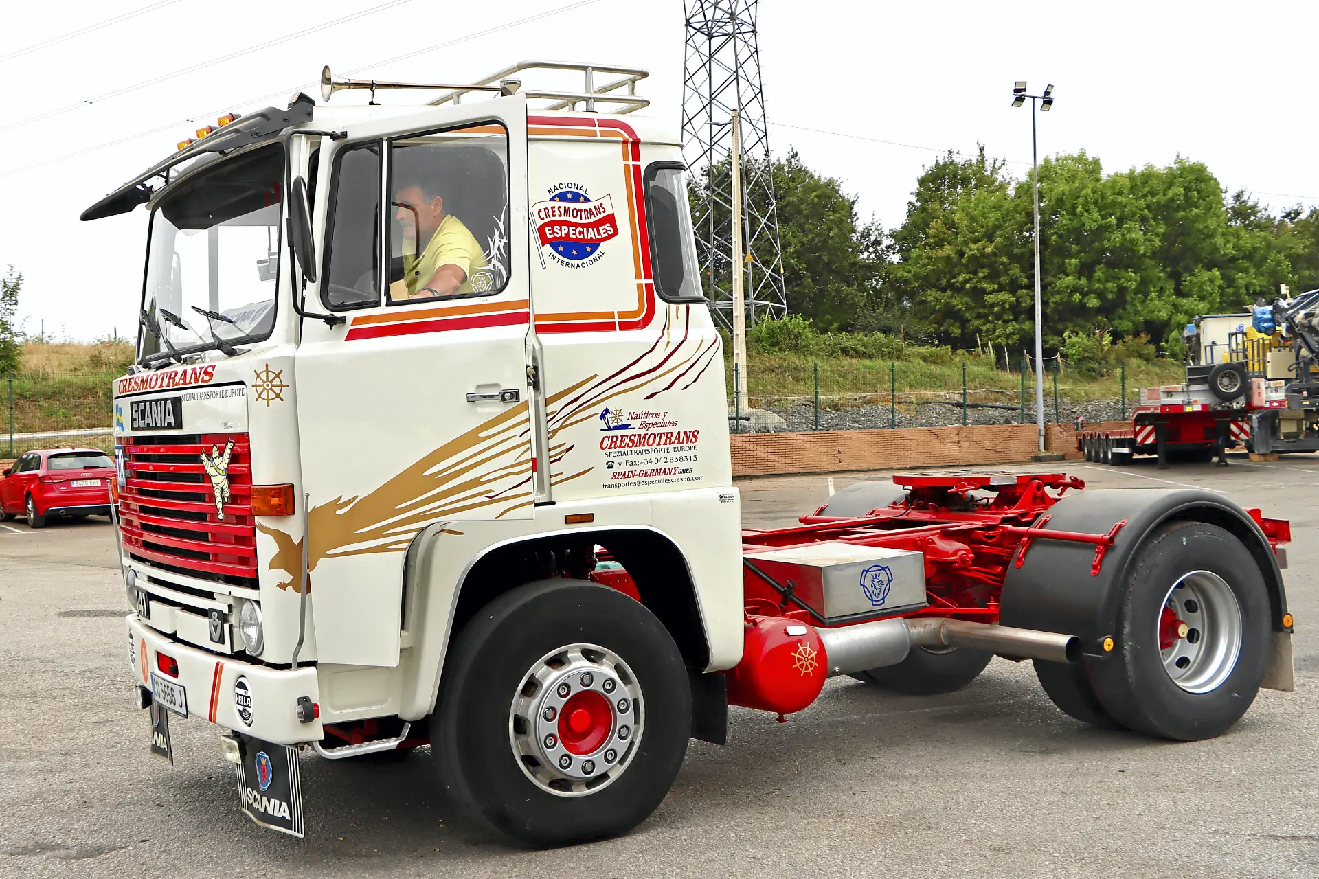 Cabina de camión Scania blanca y roja con detalles dorados aparcada al aire libre, con el conductor visible en el interior de la cabina: un buen ejemplo de camiones clásicos de Cresmotrans Náuticos & Especiales.