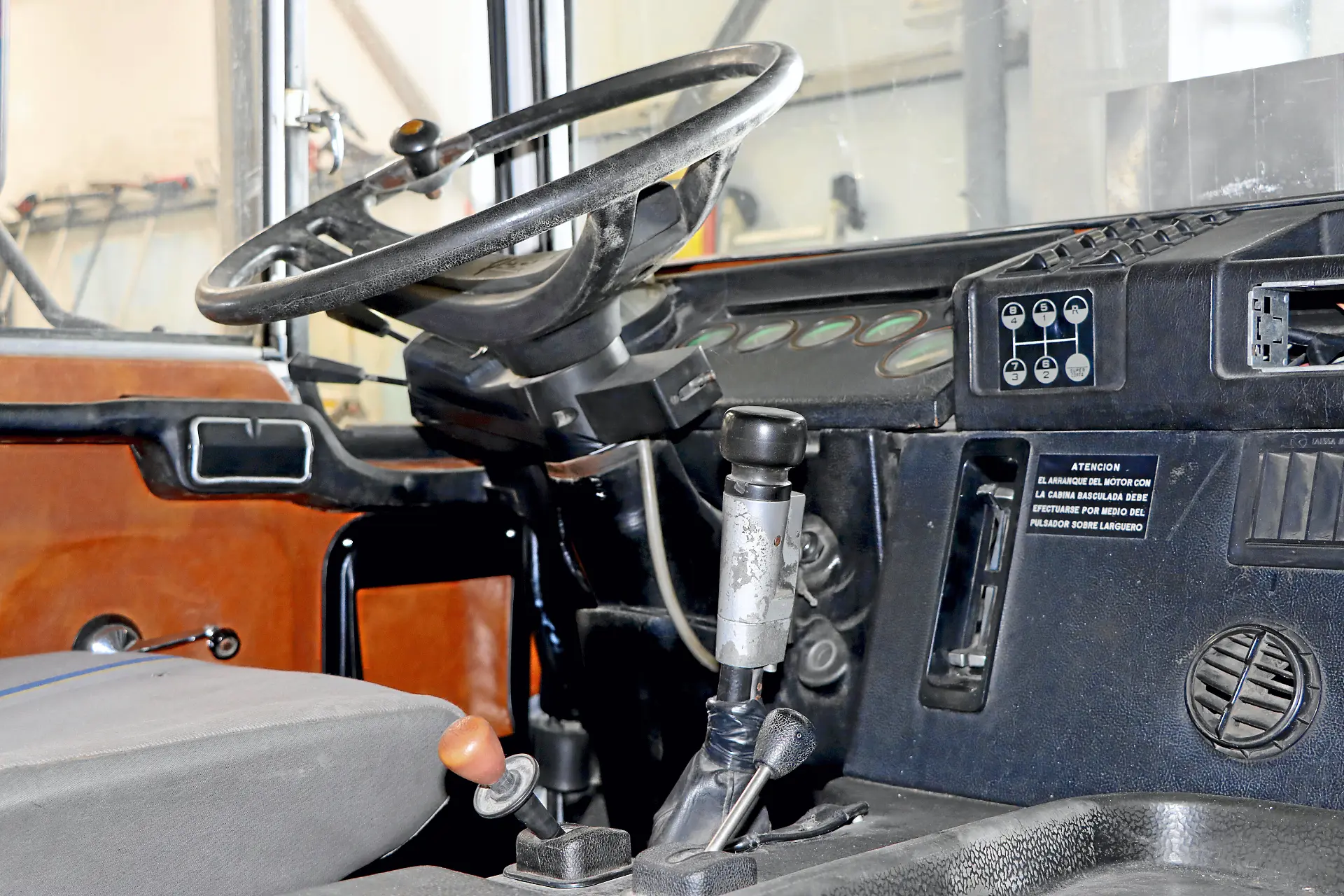 Interior de un vehículo Cresmotrans, mostrando el volante, palanca de cambios, tablero y asiento del conductor; el diseño evoca la autenticidad de los camiones clásicos y la funcionalidad de modelos Náuticos & Especiales.