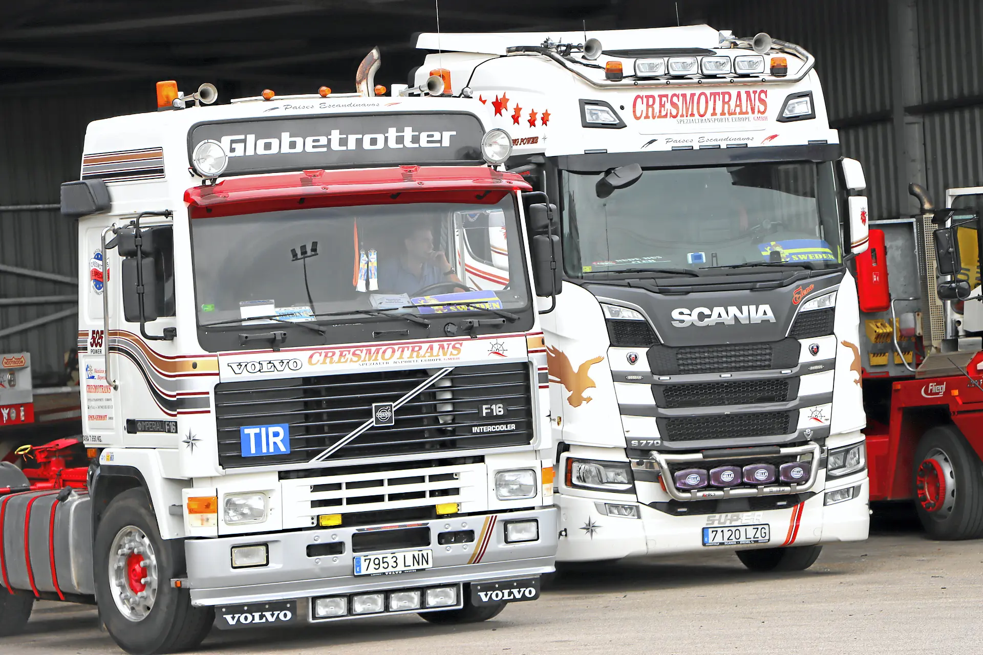 Dos grandes camiones clásicos de Cresmotrans, un Volvo y un Scania, aparcados uno junto al otro en un solar, muestran la experiencia de la marca en el transporte de Náuticos & Especiales.