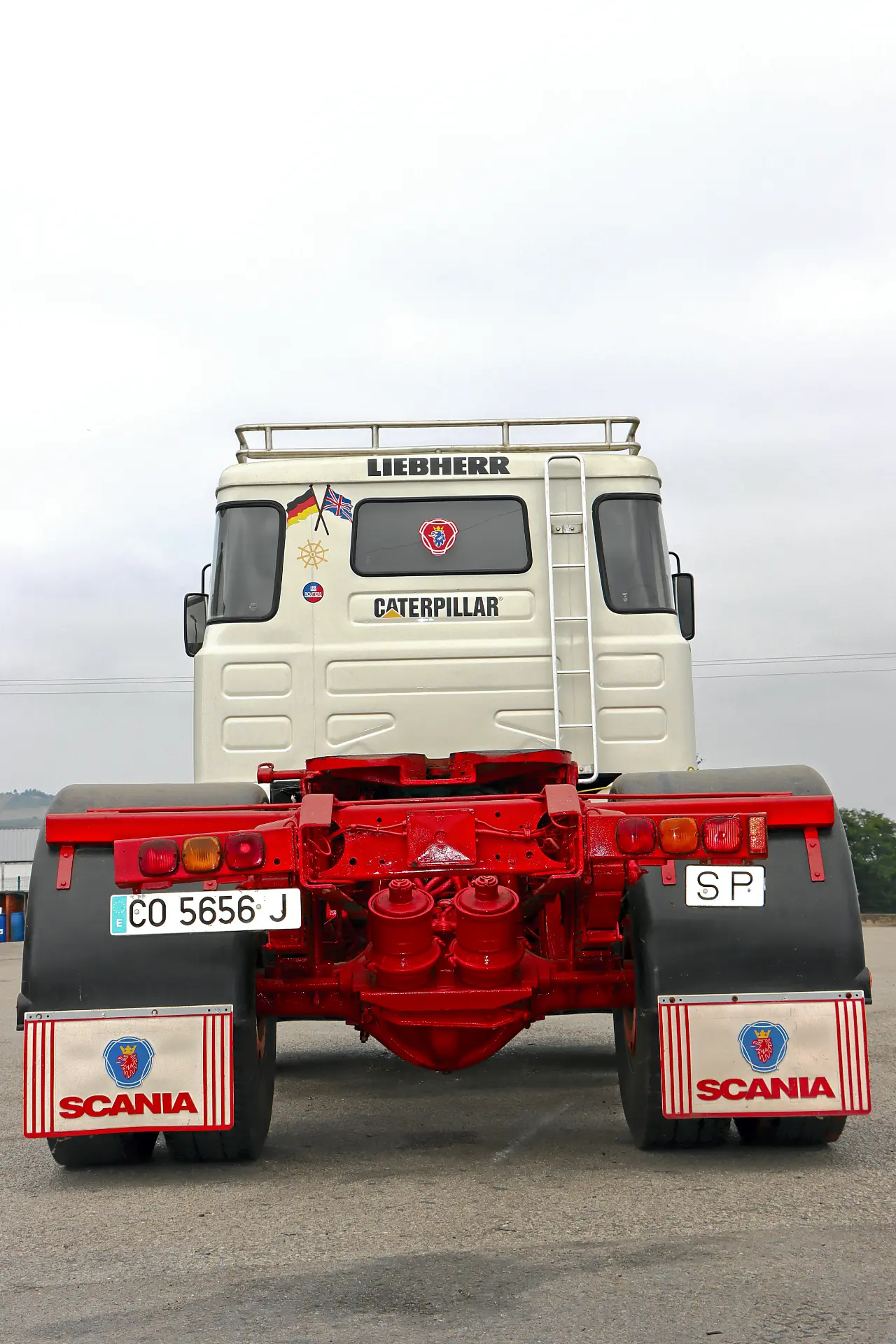 Vista trasera de una cabina de camión Scania blanca con detalles en rojo, con los logotipos de Caterpillar y Liebherr: un auténtico acontecimiento para los aficionados de Cresmotrans y los amantes de los camiones clásicos Náuticos & Especiales.
