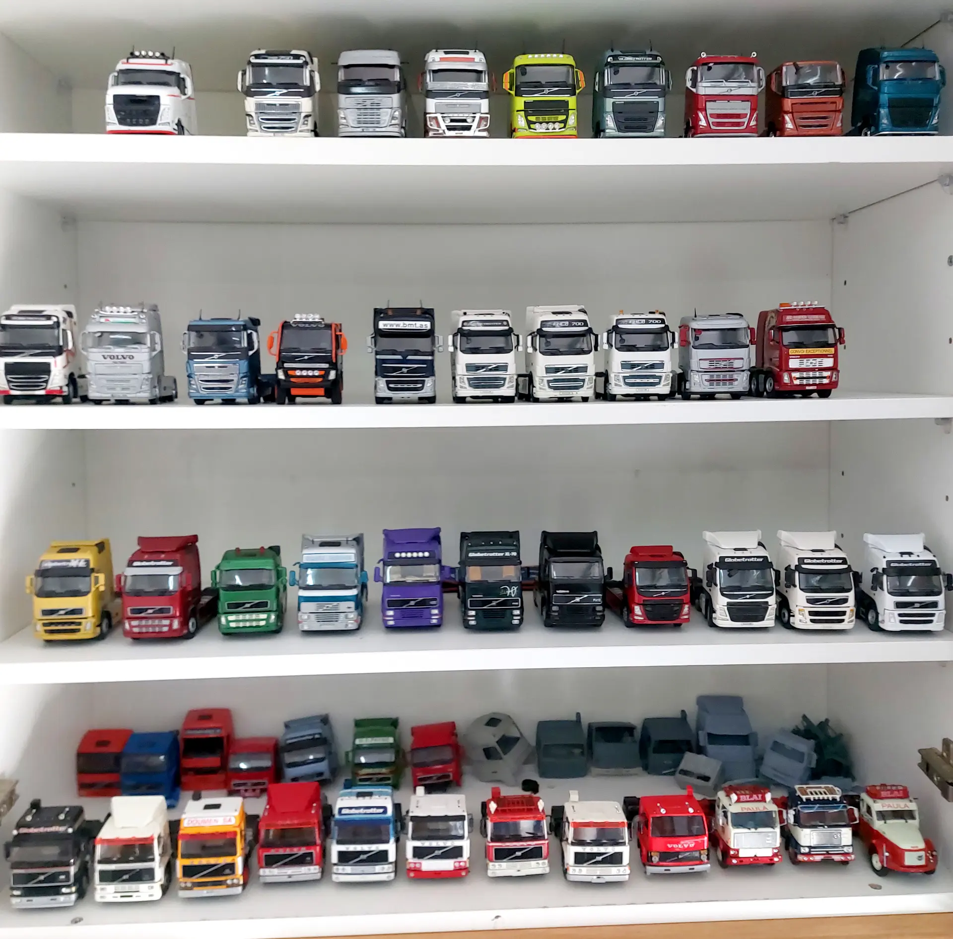 Cuatro estanterías exhiben diversas maquetas de camiones y coches de colores, dispuestas ordenadamente en filas, que reflejan la pasión de Juan Carlos Carrasco por siembre inspiración y recolecta recuerdos a través de cada pieza única.