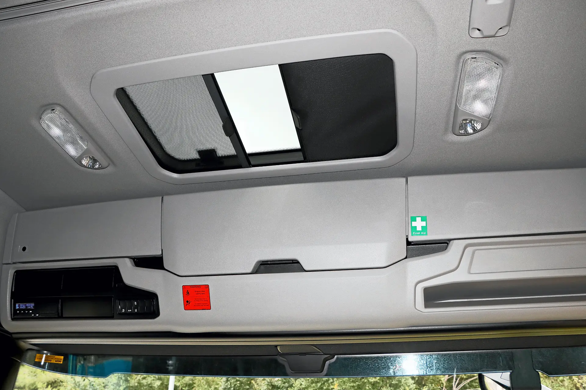 Techo de cabina de camión gris con techo solar rectangular, compartimentos portaobjetos y símbolo de botiquín.