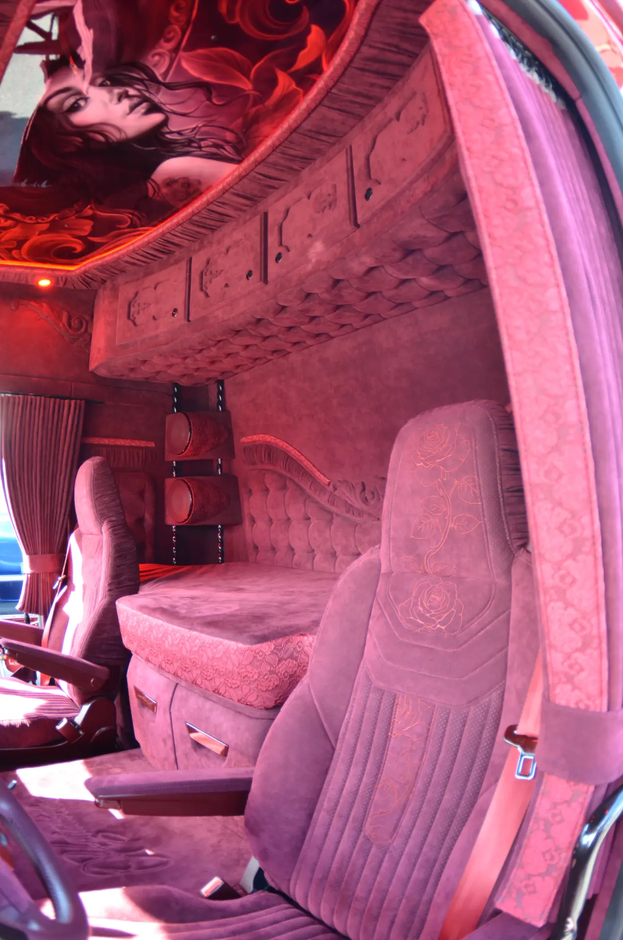 Lujoso interior de cabina de camión Scania R770 con tapicería de felpa roja, una cama y artísticos diseños florales y faciales que destilan pasión, realizado para Carmen y Sascha Heinrichs.