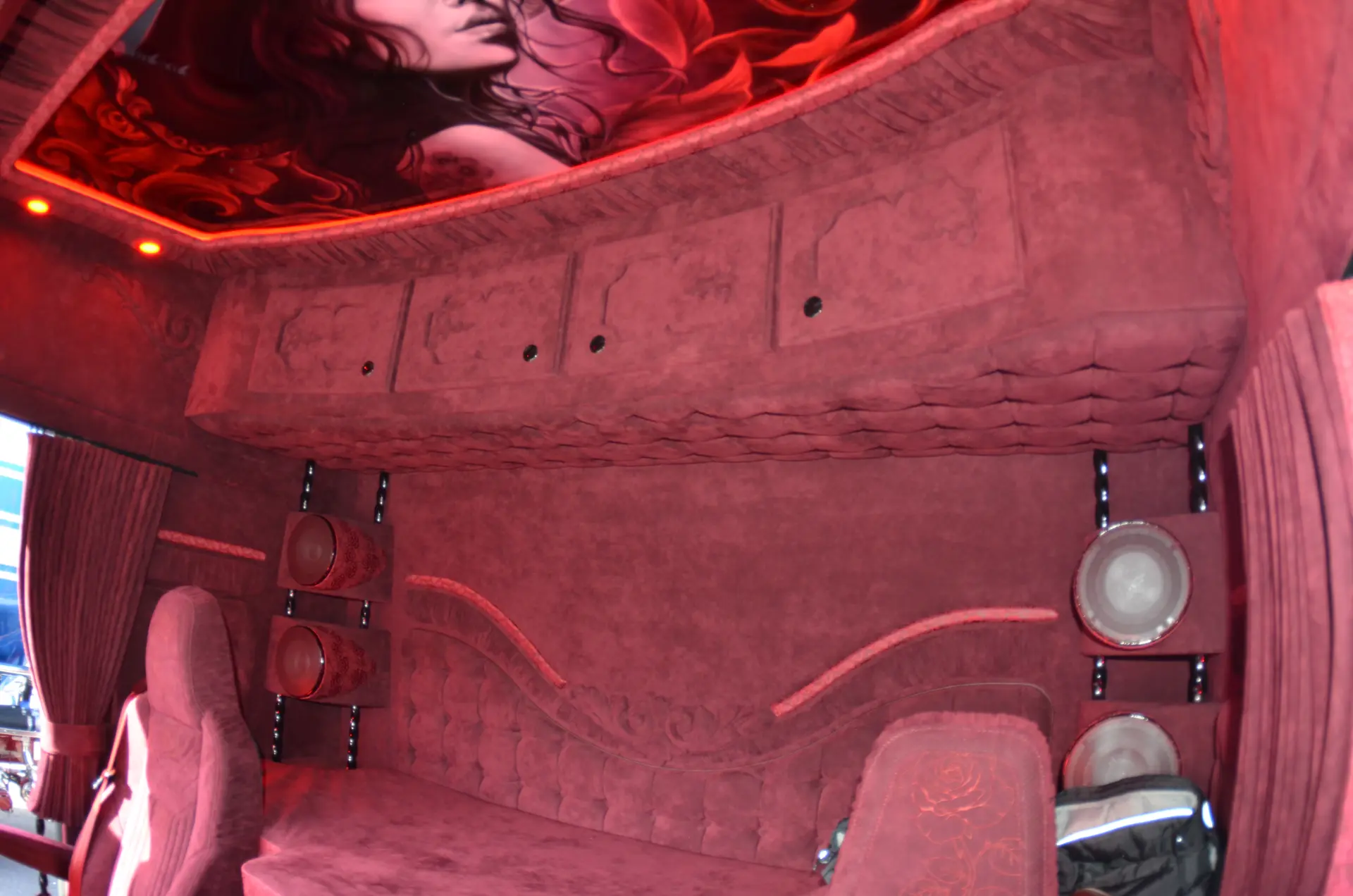 Lujosa sala de terciopelo rojo con armarios superiores, asientos de felpa y un rostro de mujer en el techo: un interior donde la pasión se une a la elegancia, inspirado en la audaz visión de Carmen y Sascha Heinrichs.