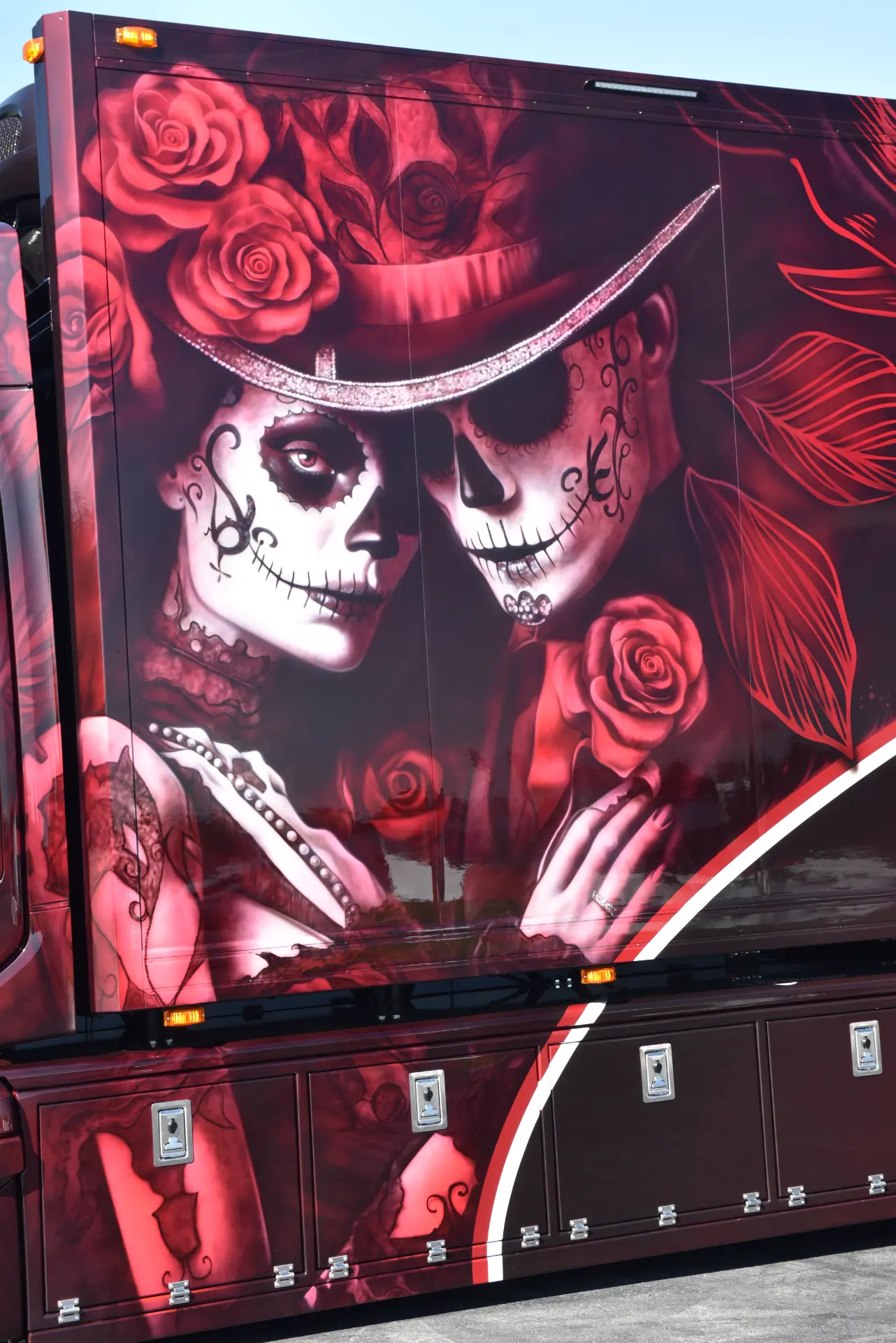 Mural del Día de los Muertos con dos figuras de esqueletos vestidos con elegantes atuendos pintados en el lateral de un Scania R770, plasmando la pasión y el arte inspirados por Carmen y Sascha Heinrichs.
