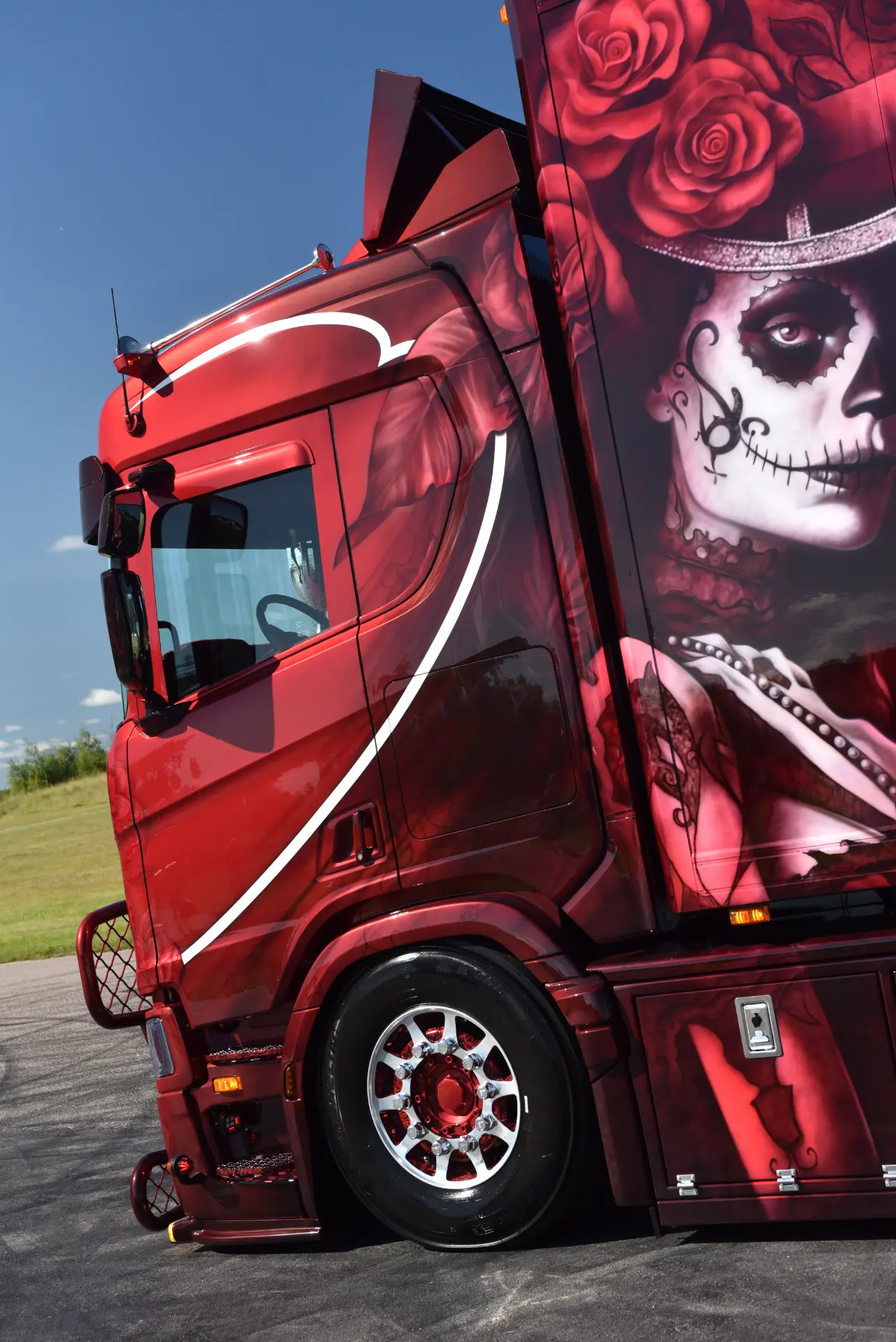 Camión Scania R770 rojo con un detallado arte de aerografía de Carmen y Sascha Heinrichs, en el que aparece una mujer maquillada para el Día de los Muertos y con rosas rojas, plasmando toda la pasión en cada trazo.