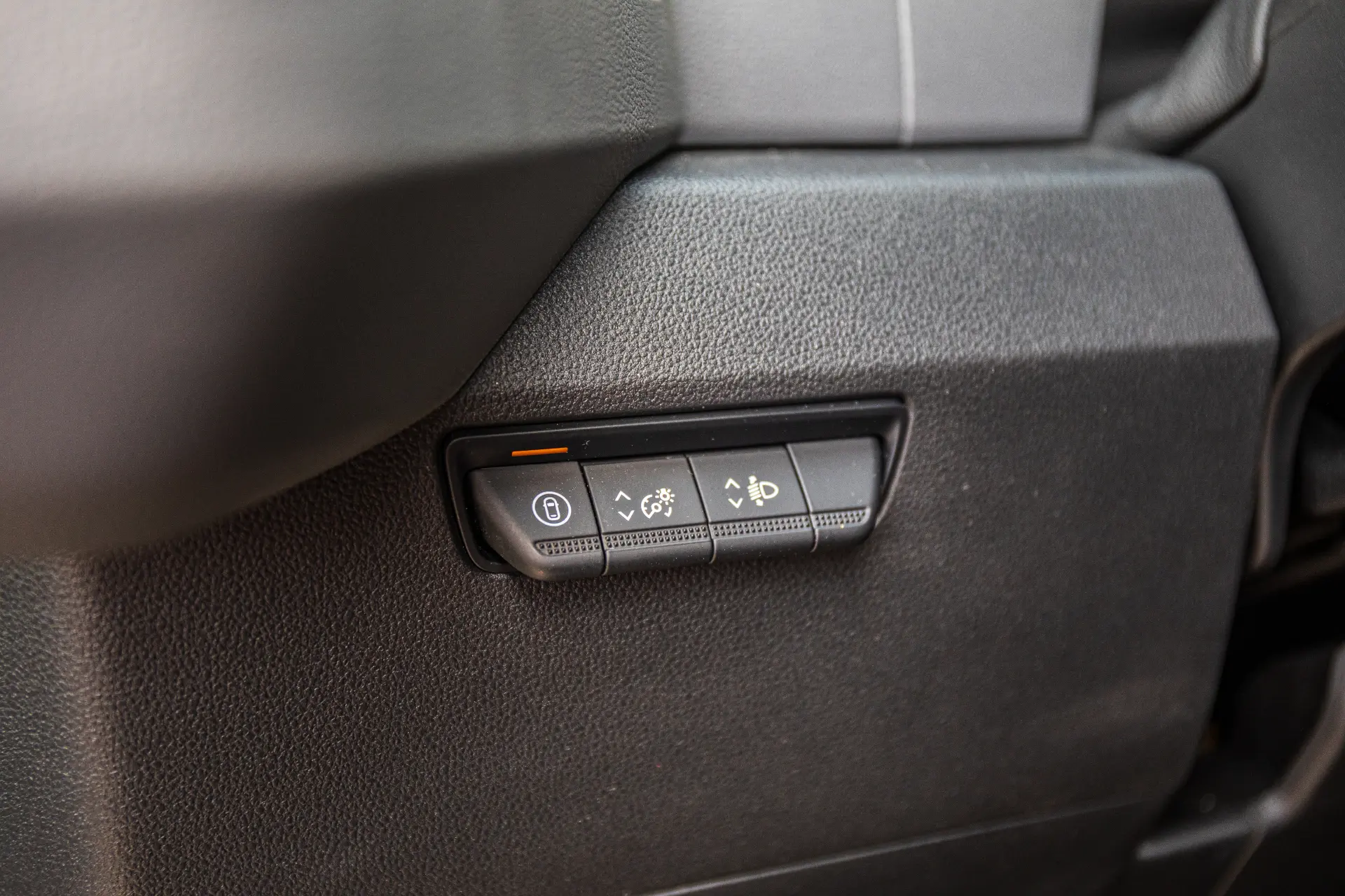 Detalle de los botones del salpicadero del Renault Master para el Head-up Display, el brillo y el ajuste del ángulo de los faros, destacando las características clave del furgón Renault.