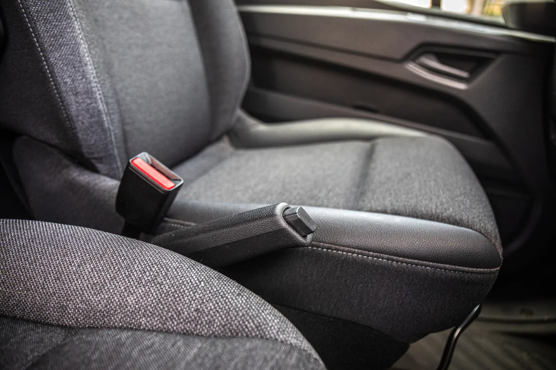 Primer plano de un asiento delantero de furgón Master, con la hebilla del cinturón de seguridad y el freno de mano visibles, para mostrar el confort y la seguridad de las furgonetas eléctricas Renault Trucks Master.