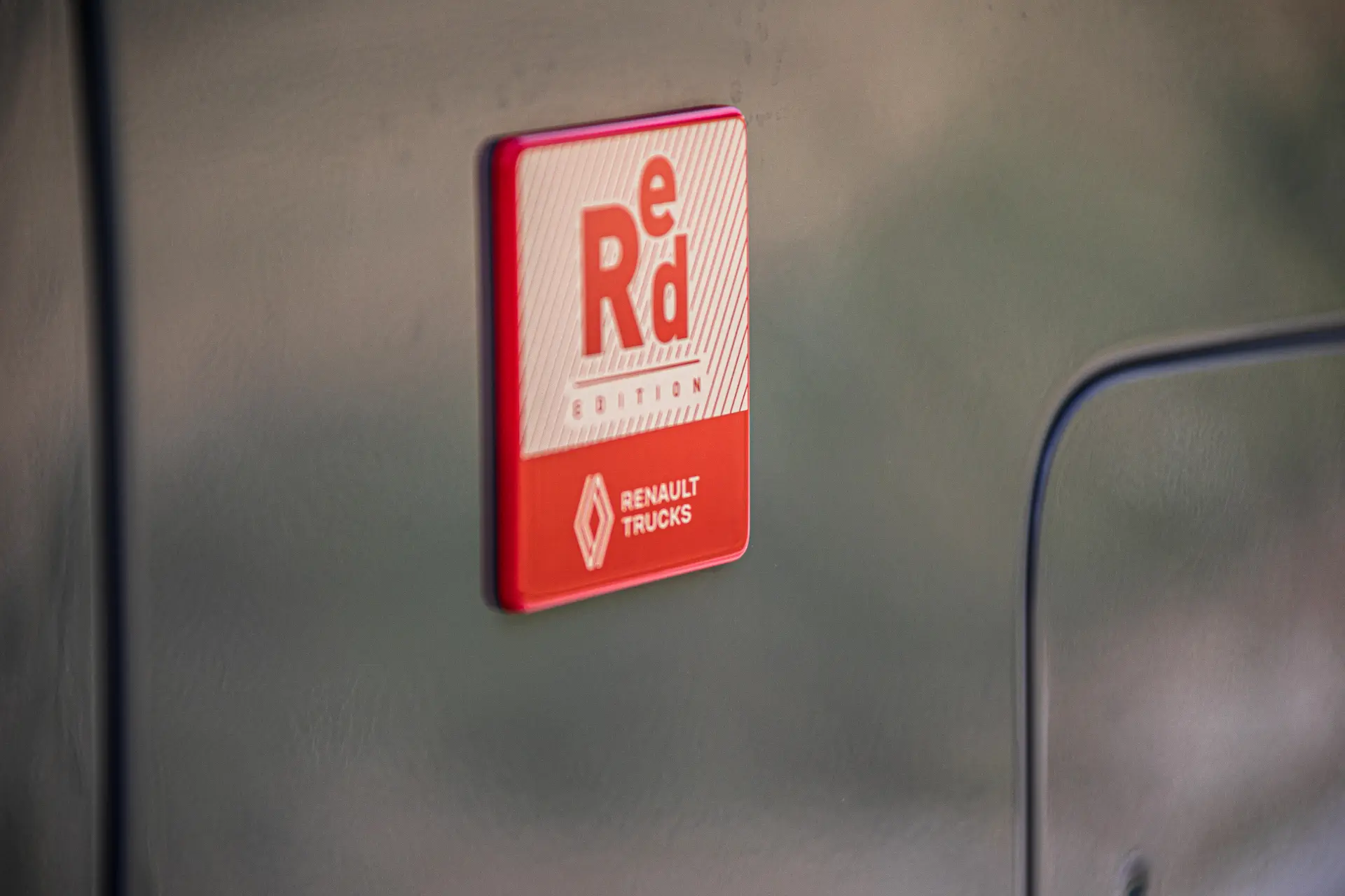 Primer plano de un distintivo rojo y blanco de Renault Trucks con la inscripción "e Rd Edition" sobre una superficie gris furgón Renault Master.