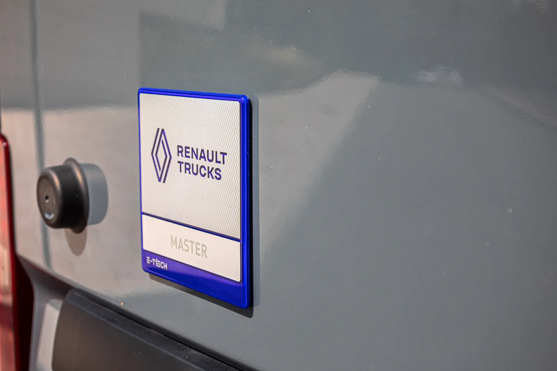 Primer plano de un distintivo Renault Trucks Master en el lateral de un furgón Renault Master gris.