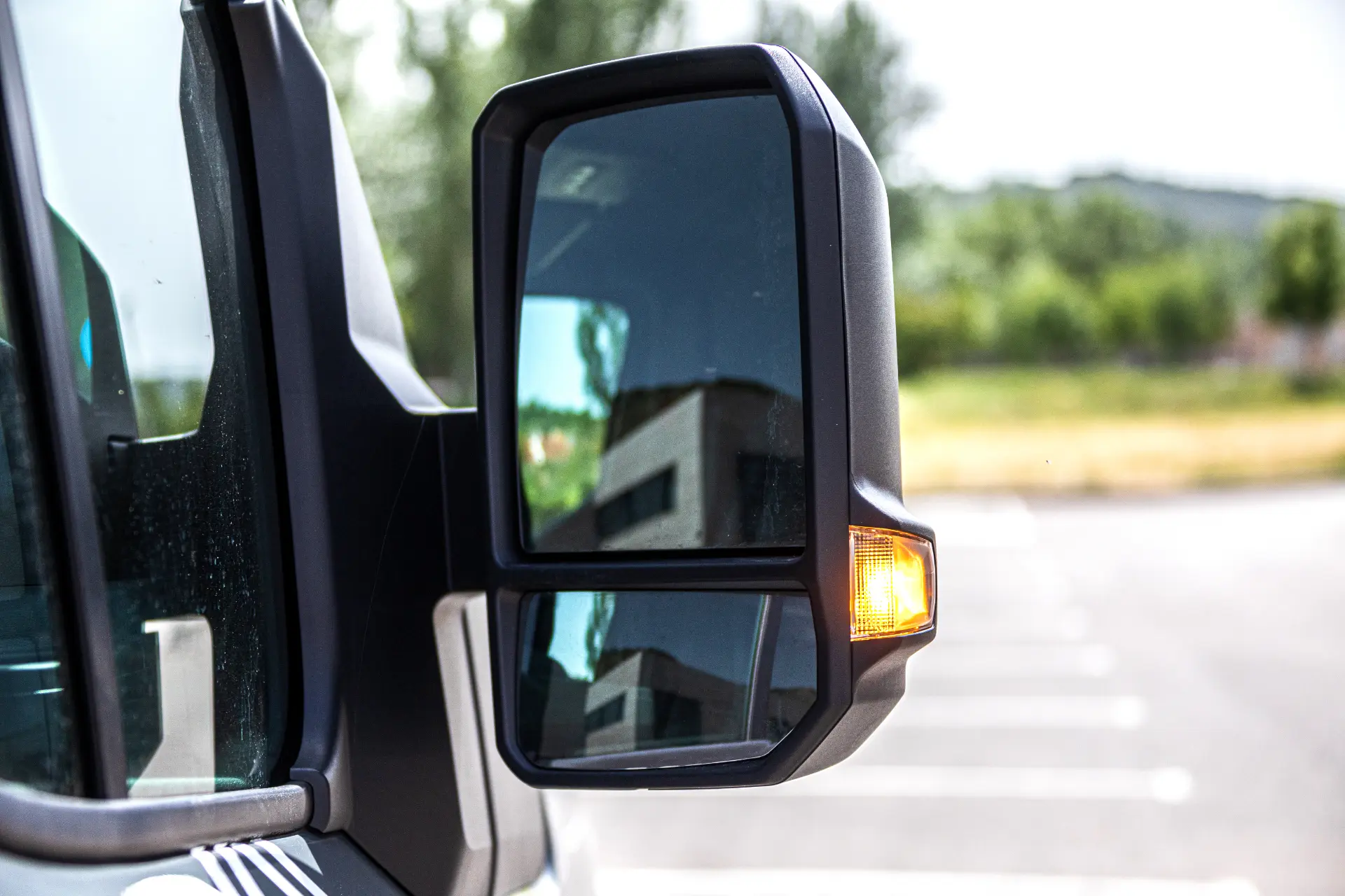 Primer plano del retrovisor lateral de un Renault Trucks Master E-Tech L3H2 con un intermitente ámbar iluminado en un aparcamiento durante una prueba.