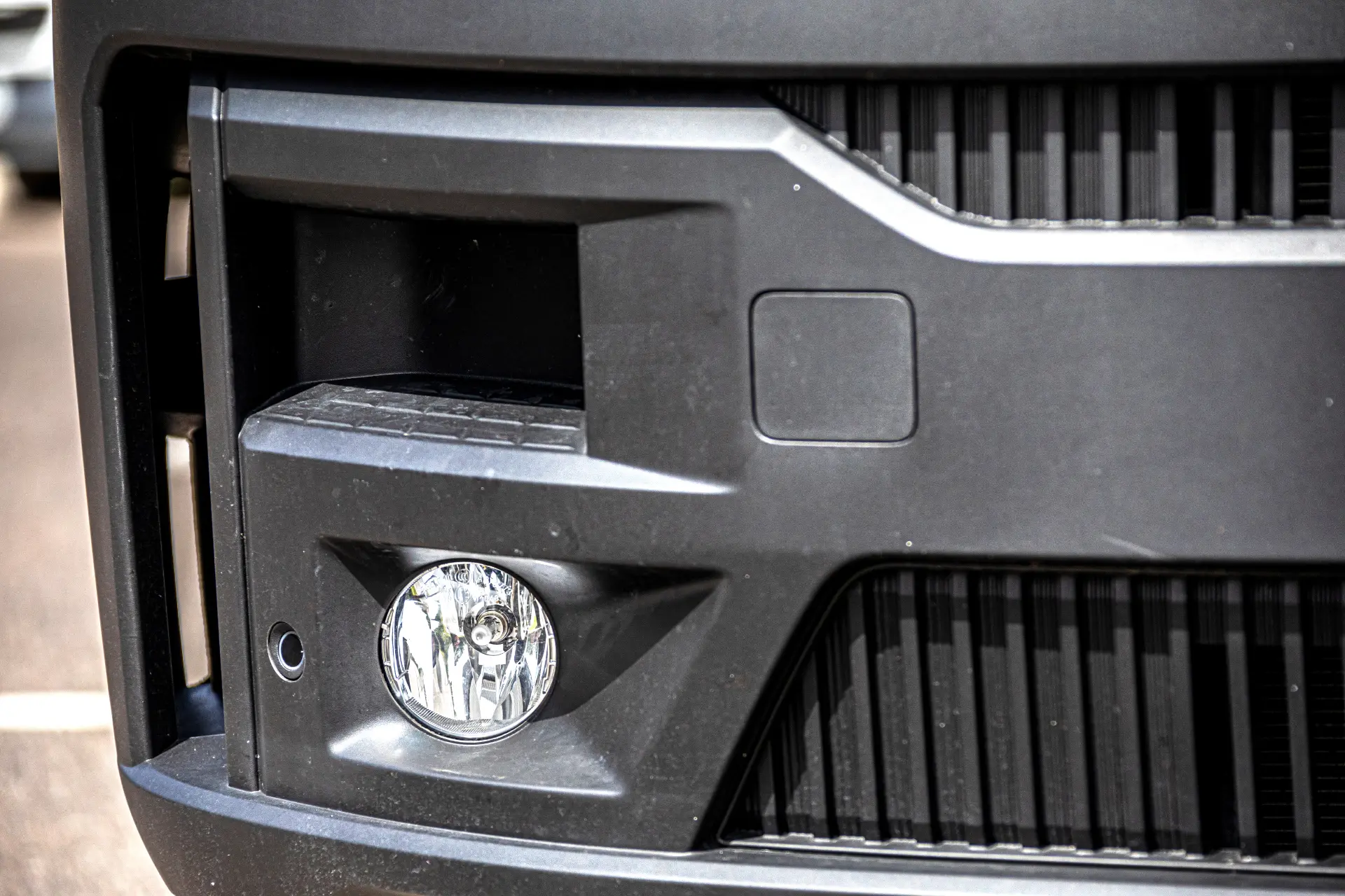 Primer plano de un parachoques Renault Master negro con una luz antiniebla redonda y detalles en la parrilla.