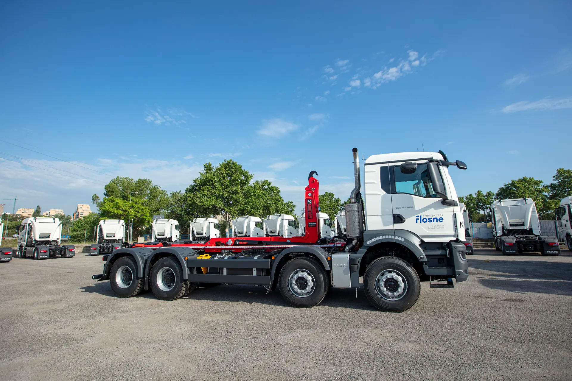 Un camión MAN blanco de gran tonelaje y seis ruedas, fabricado por carroceros, está aparcado en un solar junto a camiones similares en un día despejado, mostrando una solución 360 para las necesidades de transporte.