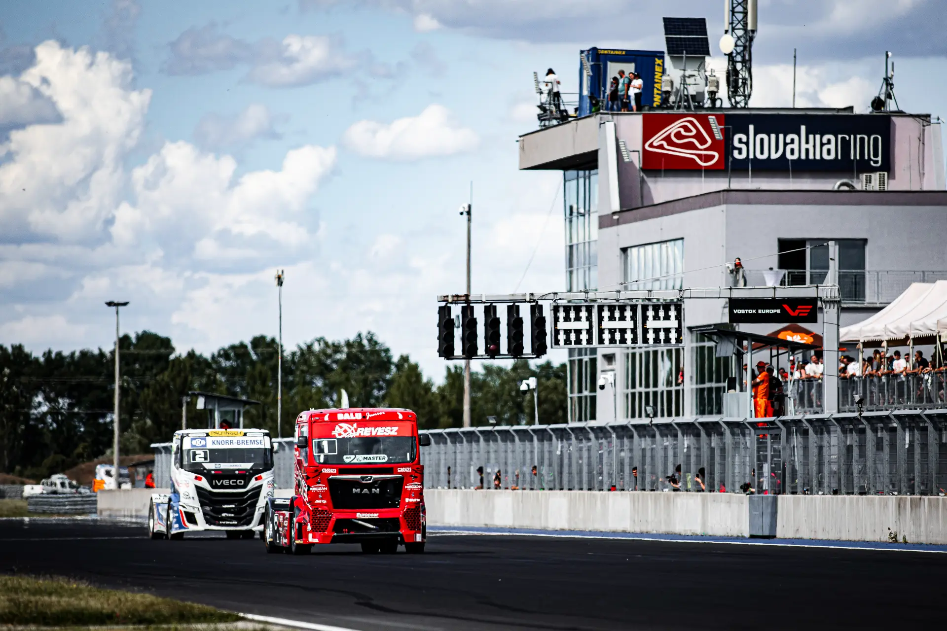 Dos camiones de carreras pasan a toda velocidad por delante de la torre de control del circuito de Eslovaquia Ring, captados como congelados por un borrador automático.