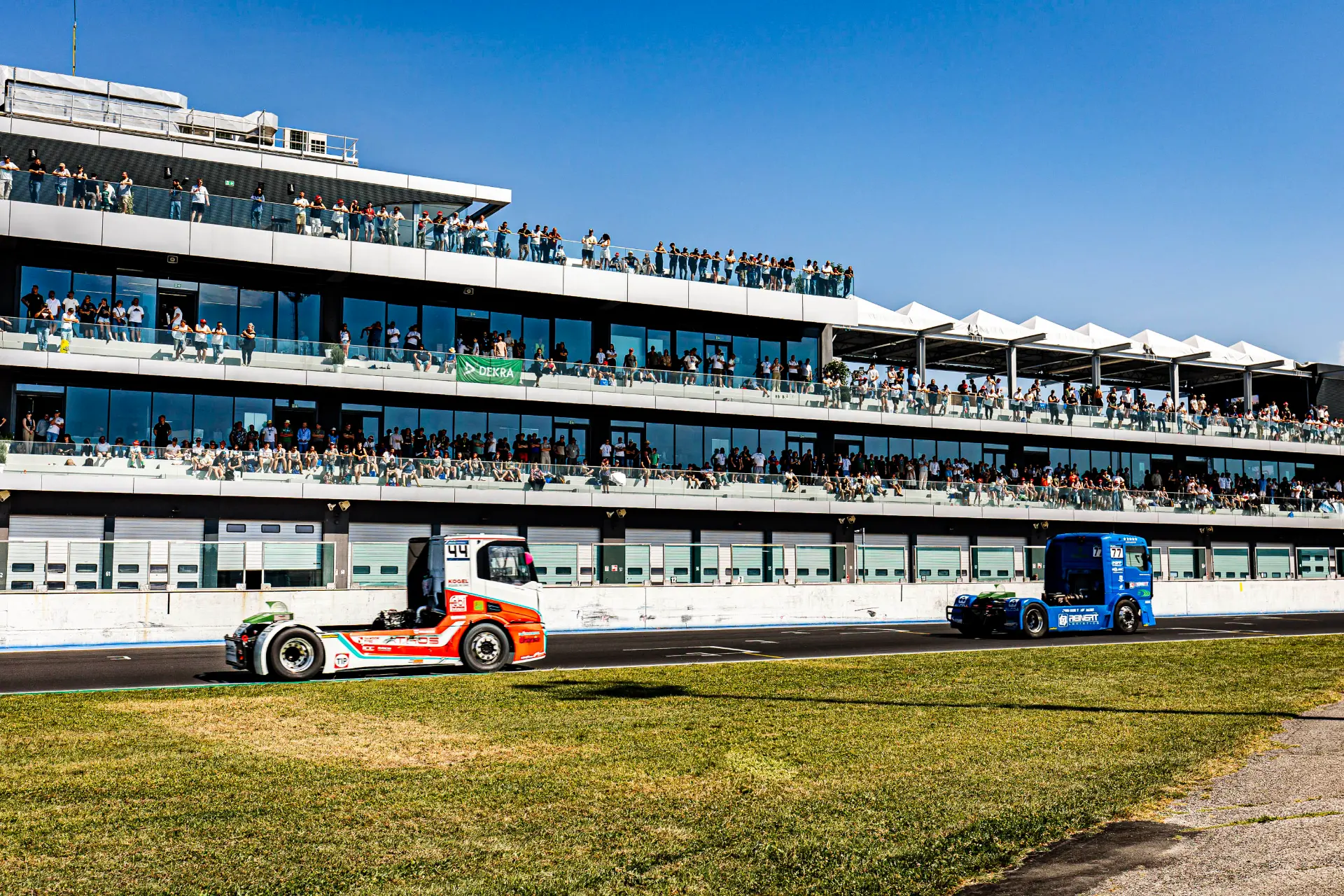 Dos camiones de carreras pasan a toda velocidad por delante de una grada llena de espectadores en un evento automovilístico en un día soleado, mostrando la emoción del Goodyear FIA ETRC en Europa Misano ETRC 2026.