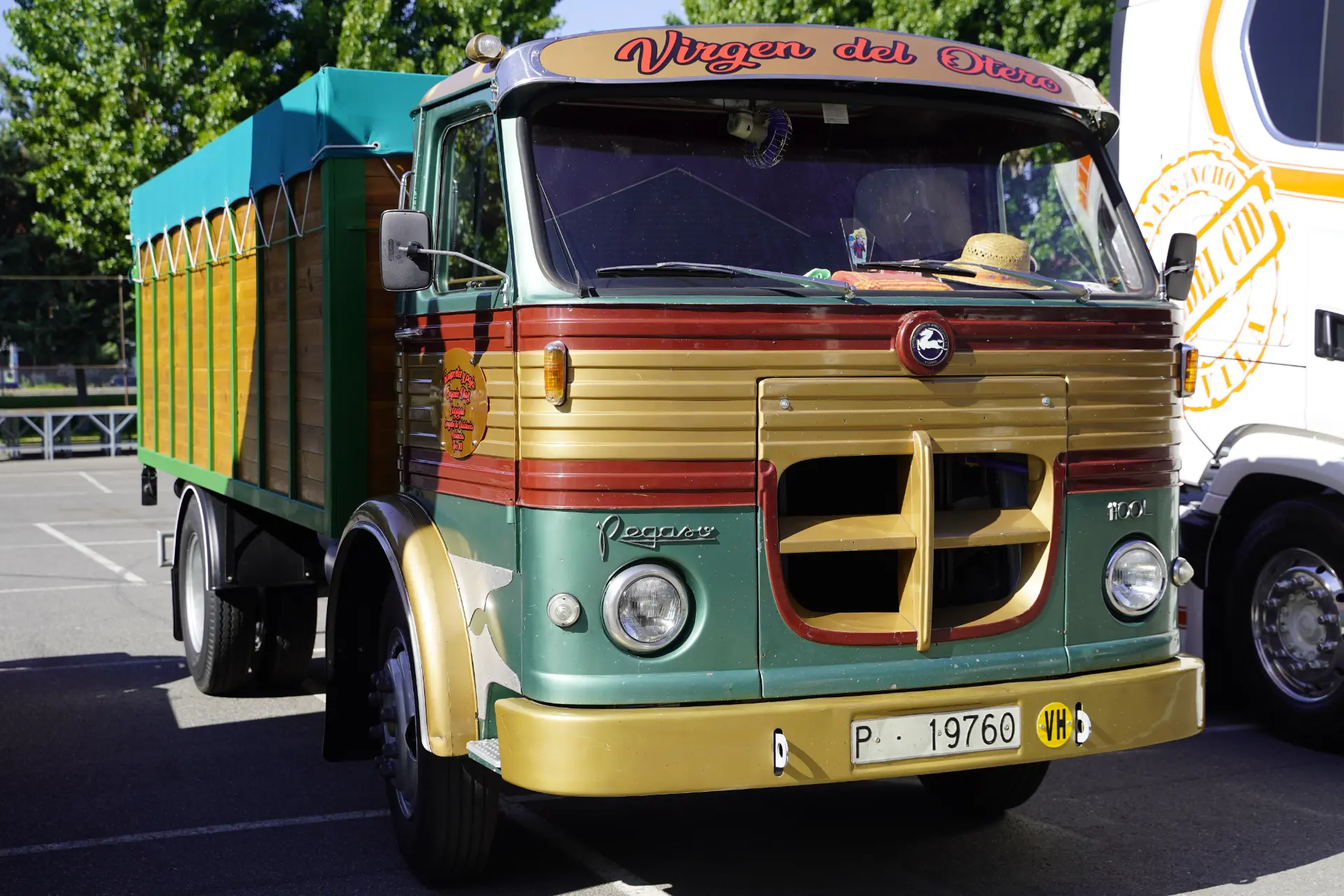 Camión Pegaso vintage verde y amarillo con zona de carga cubierta aparcado en un solar en un día soleado durante la concentración solidaria de camiones en Ávila, con 95 vehículos.
