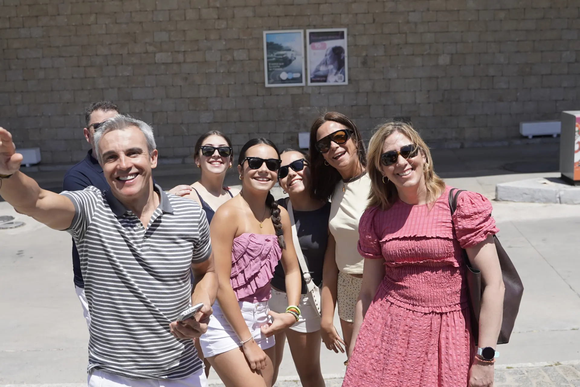Un grupo de seis personas sonrientes posan al aire libre en un día soleado en Ávila, todos con gafas de sol, disfrutando de la concentración solidaria de camiones.