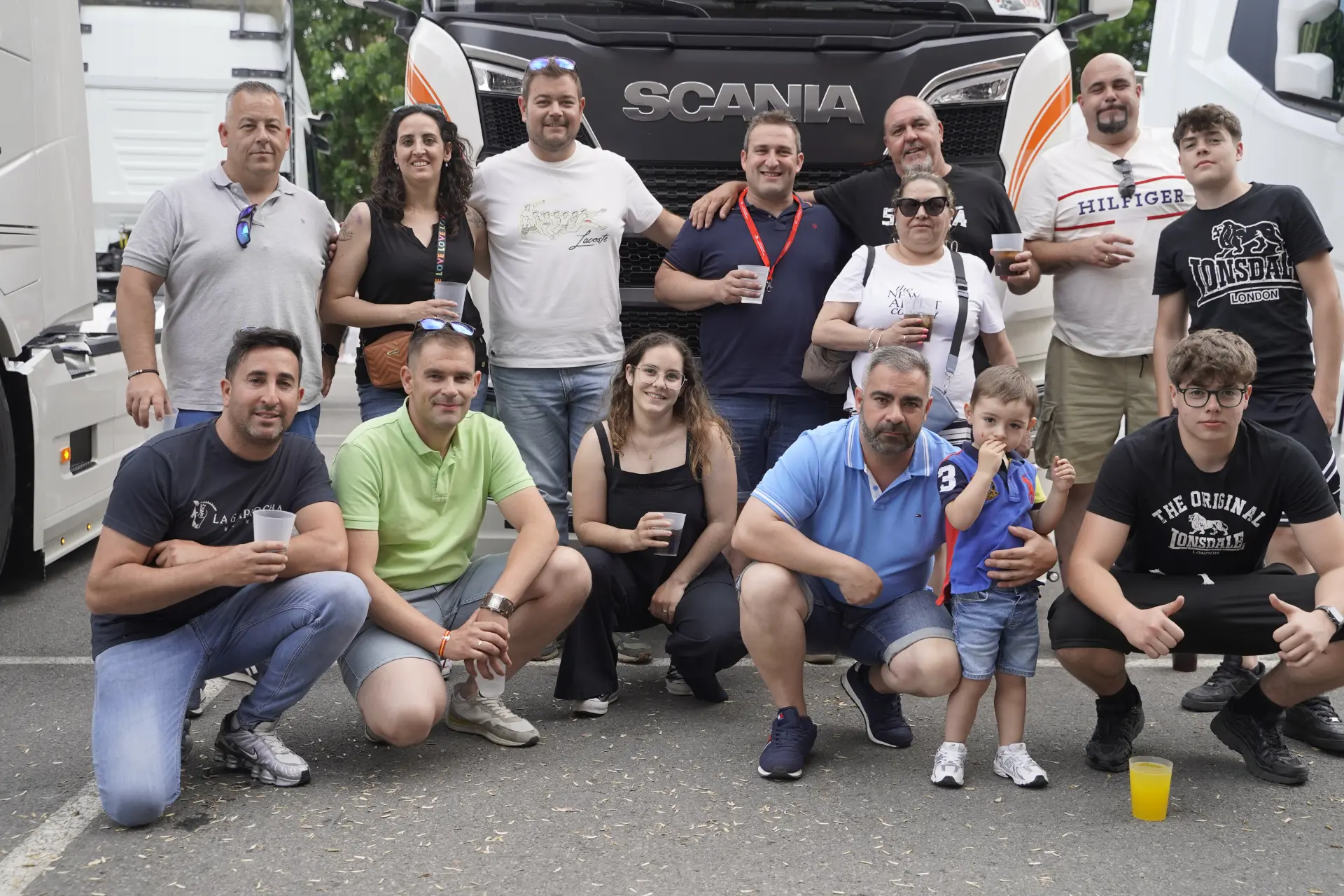 Un grupo de personas posa y sonríe junto a un gran camión Scania en la concentración solidaria de camiones en Ávila.