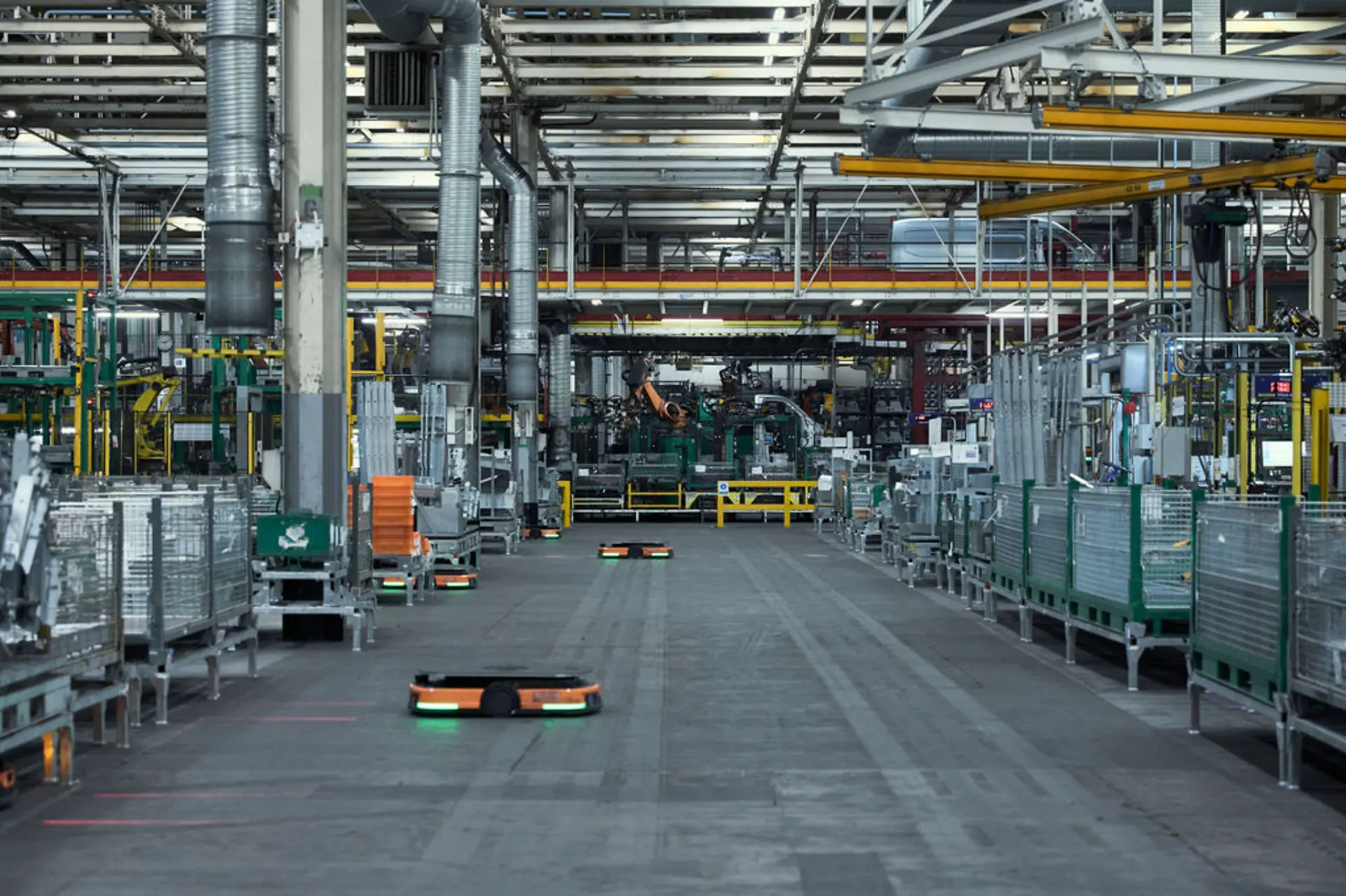 Unos robots automatizados se desplazan por un amplio pasillo dentro de la moderna y bien iluminada fábrica o planta industrial de Renault en Batilly.